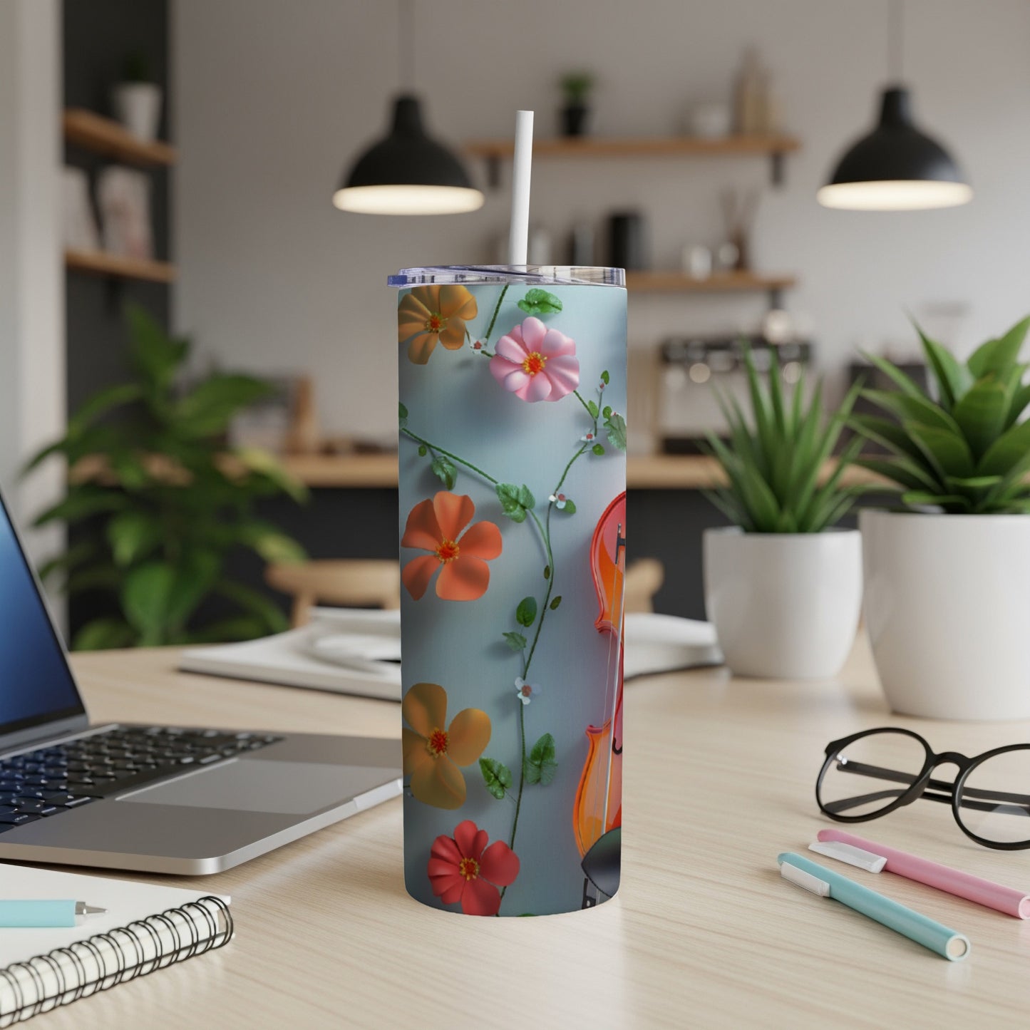 Tumbler with floral design on a desk next to a laptop.