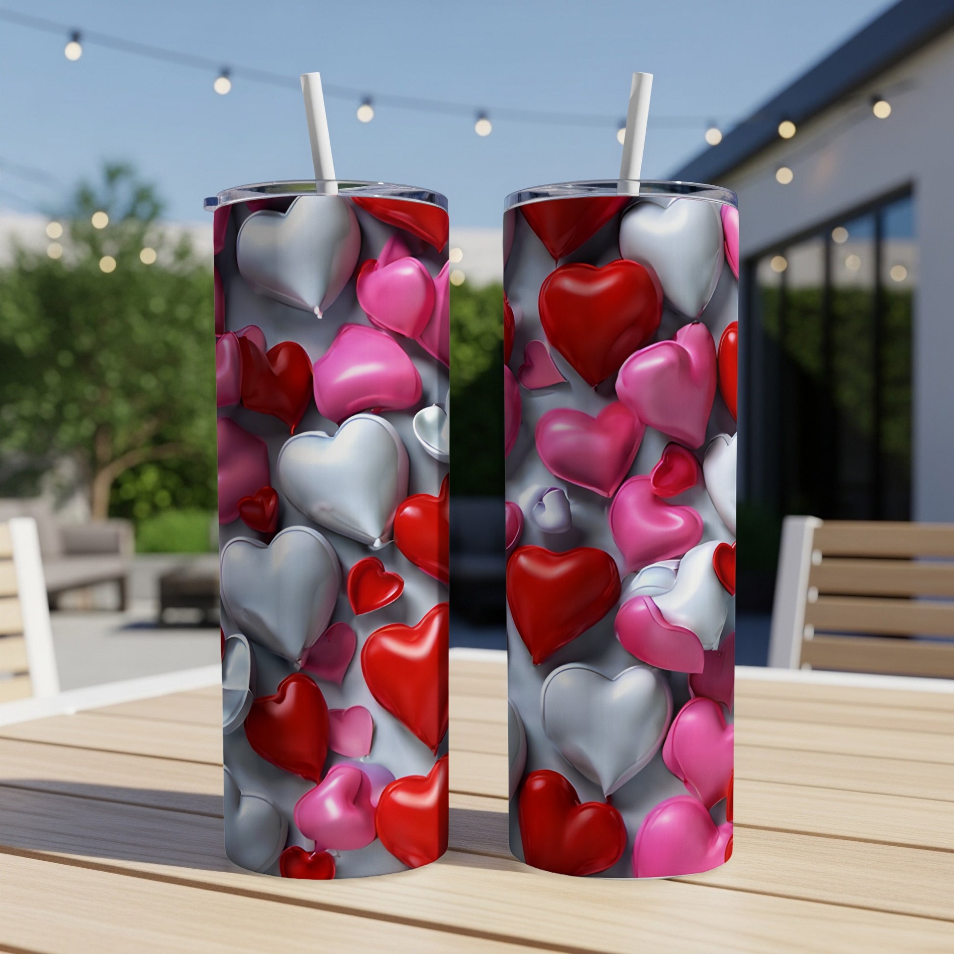 Two tumblers with a scattered heart design sit on an outdoor table.
