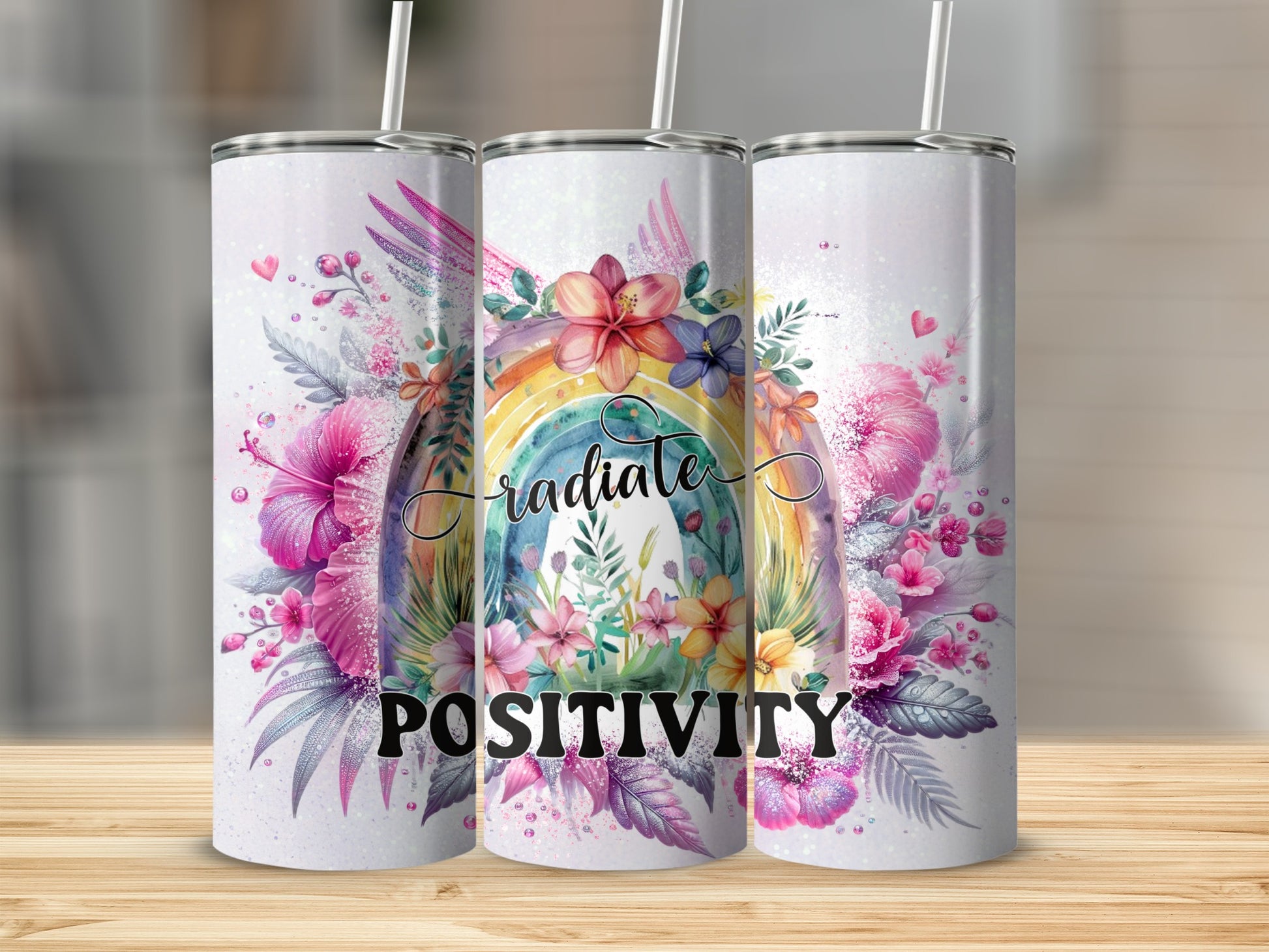 Three tumblers with rainbow and floral design saying "Radiate Positivity."