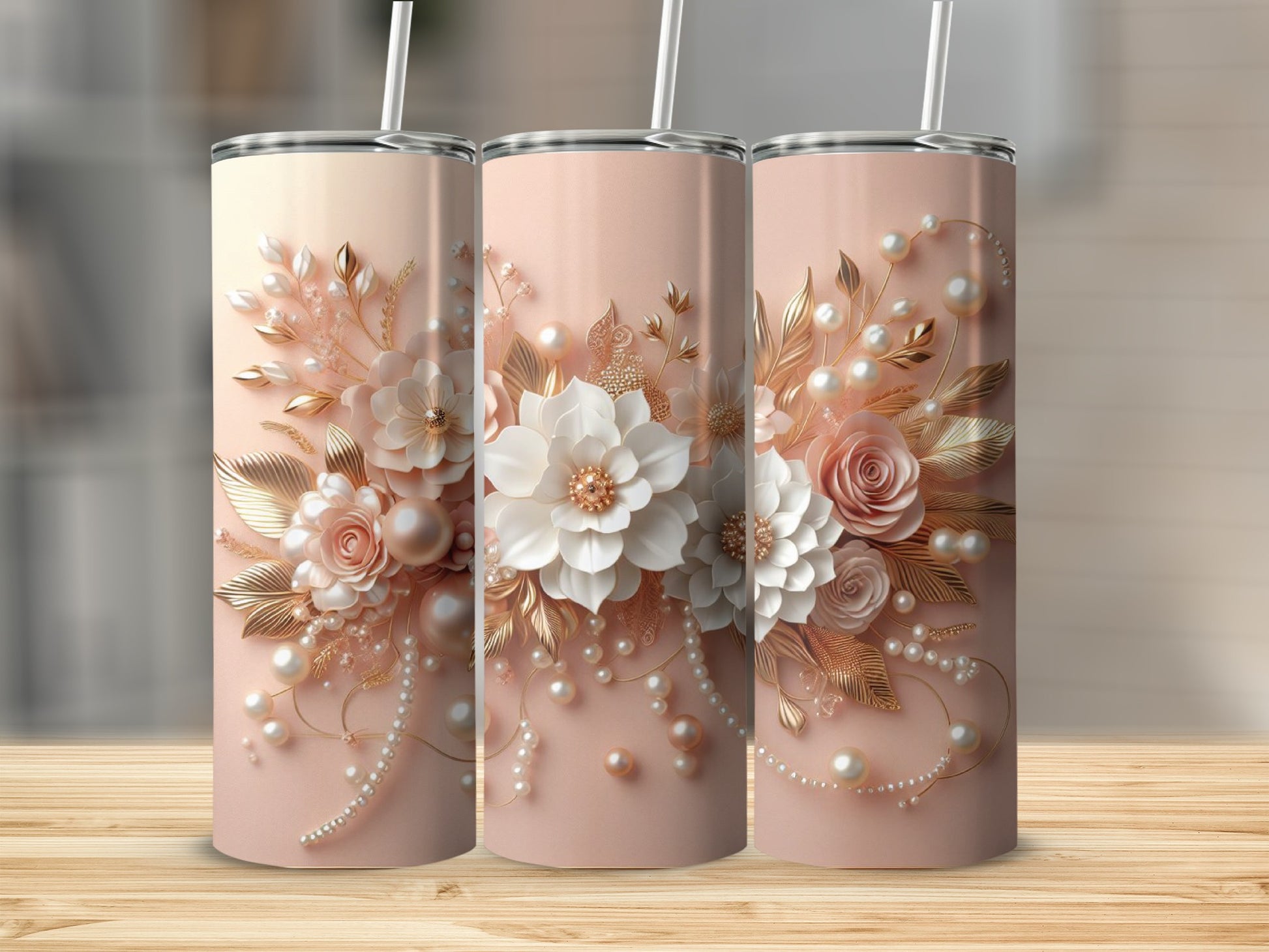 Three rose gold tumblers with floral and pearl embellishments on a wooden surface.