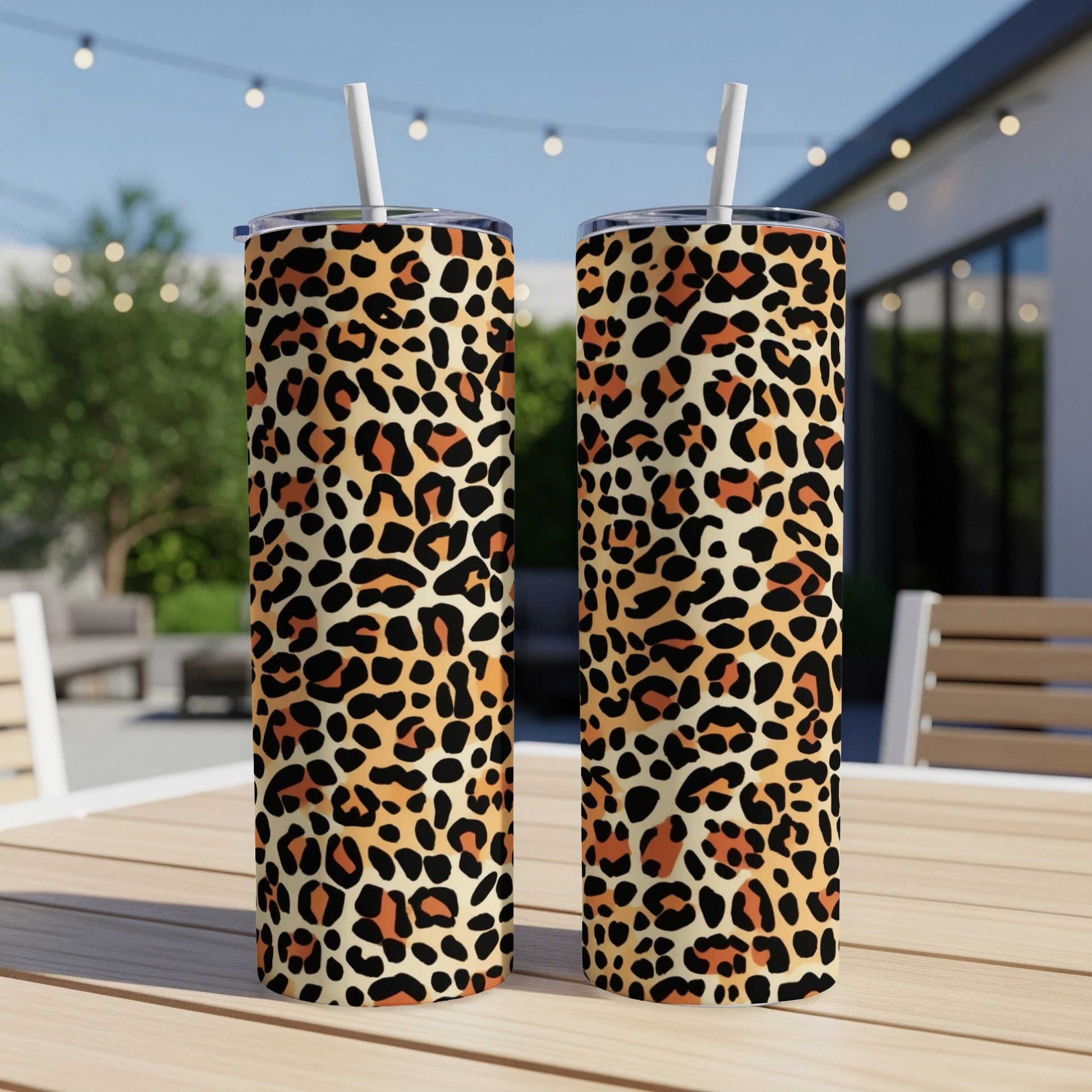 Two leopard print tumblers with straws on a wooden table.