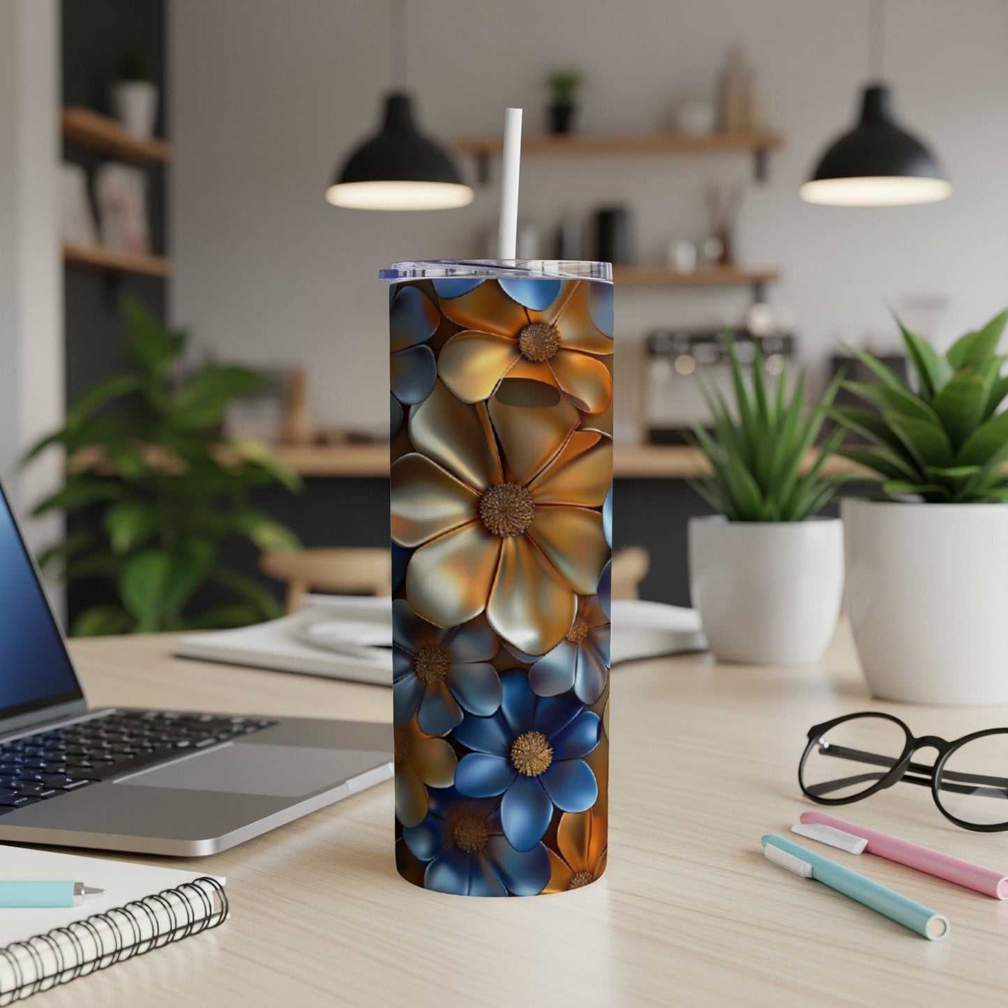 Tall tumbler with blue and gold floral pattern on a desk.