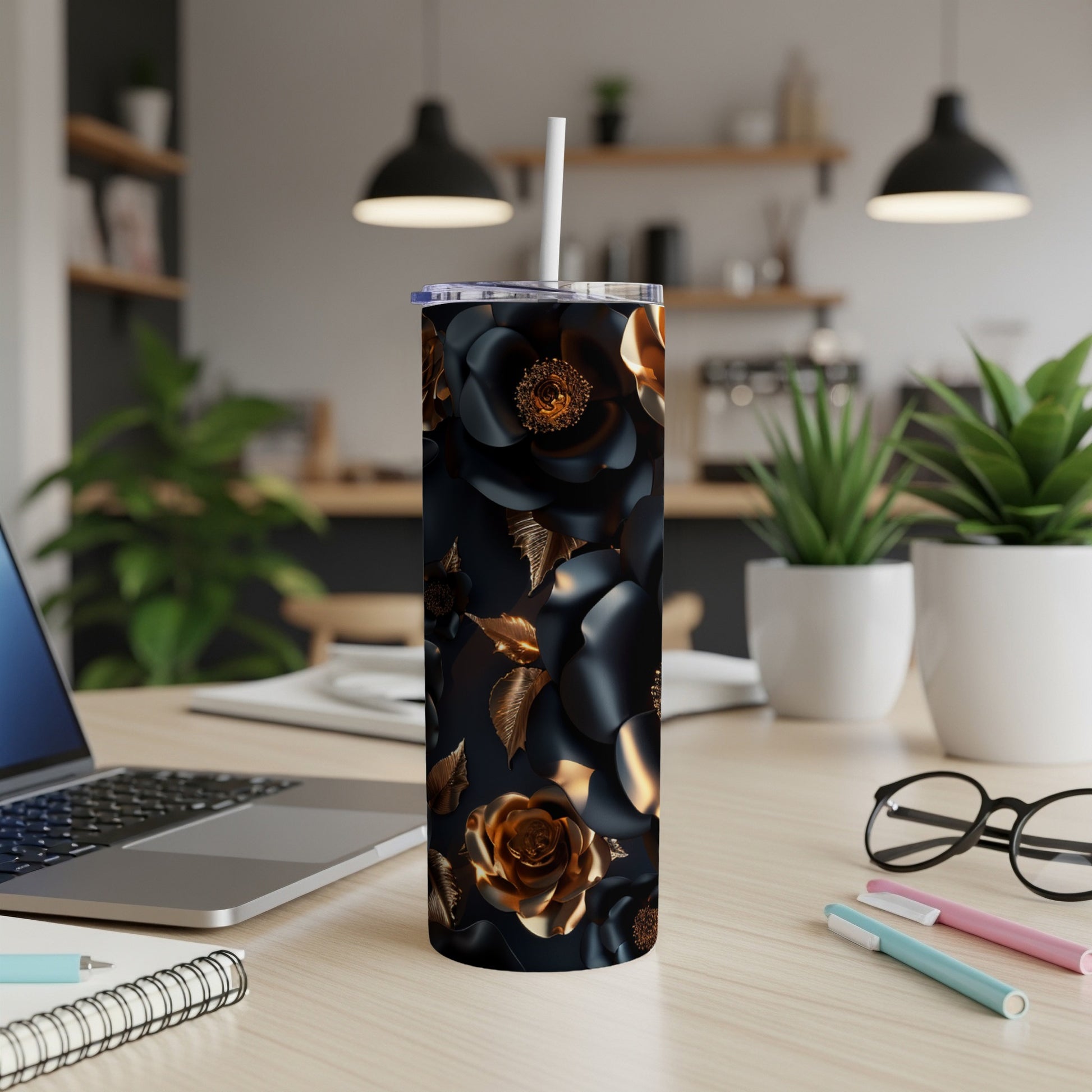 Black and gold floral tumbler with straw on desk.