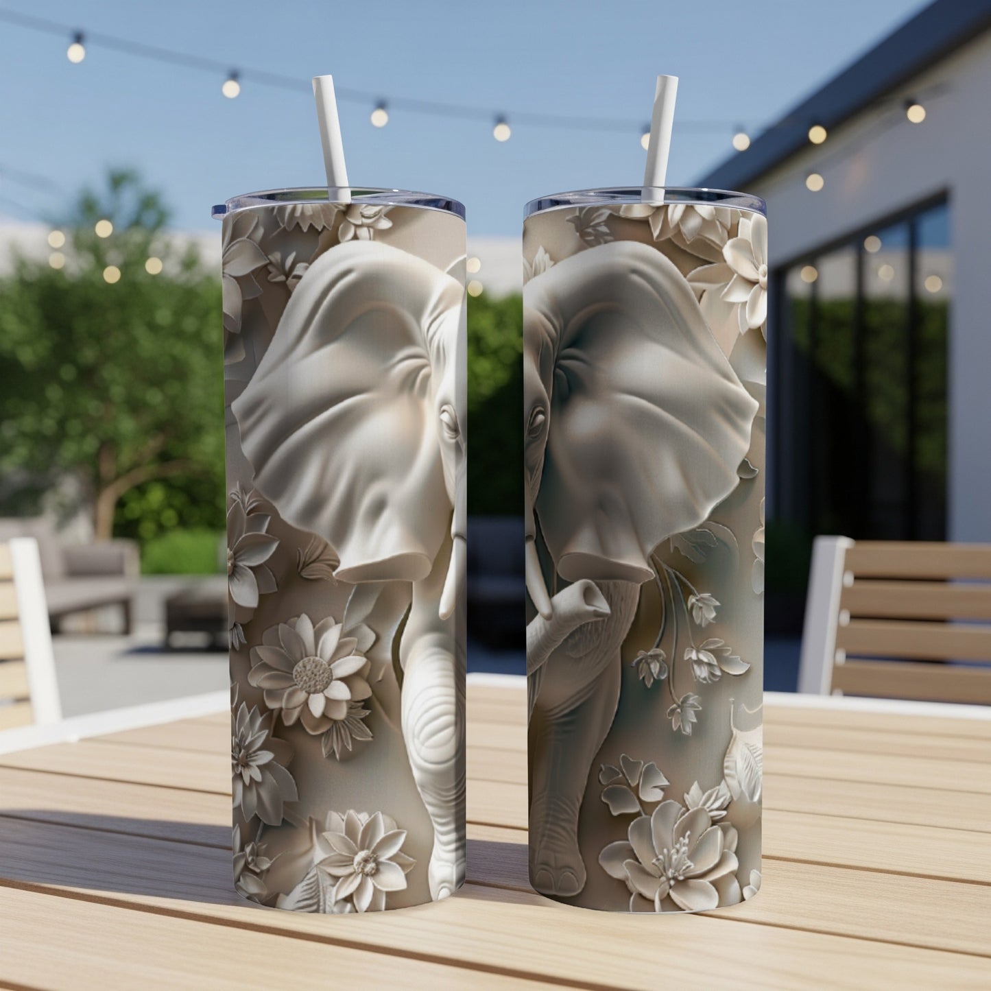 Two tumblers with embossed elephant and floral designs on a wooden table.