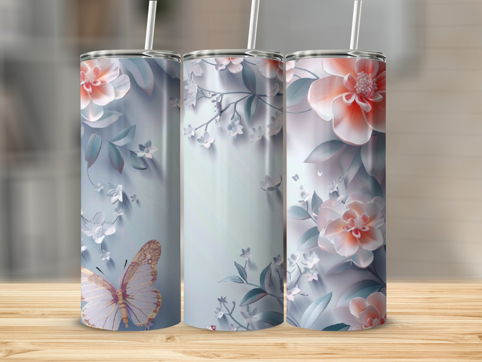 Three tumblers with floral and butterfly designs, displayed on a wooden surface.