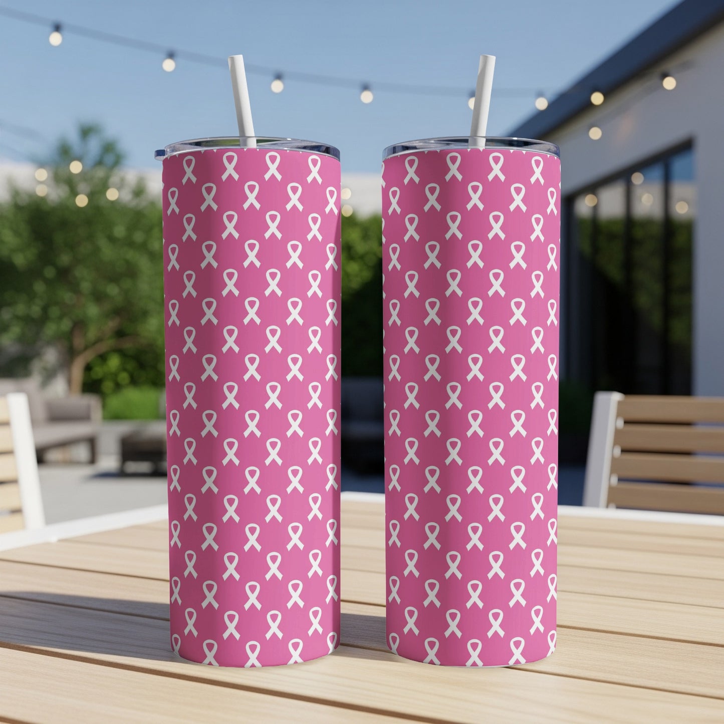 Two pink tumblers with white ribbon pattern and straws, displayed outdoors.