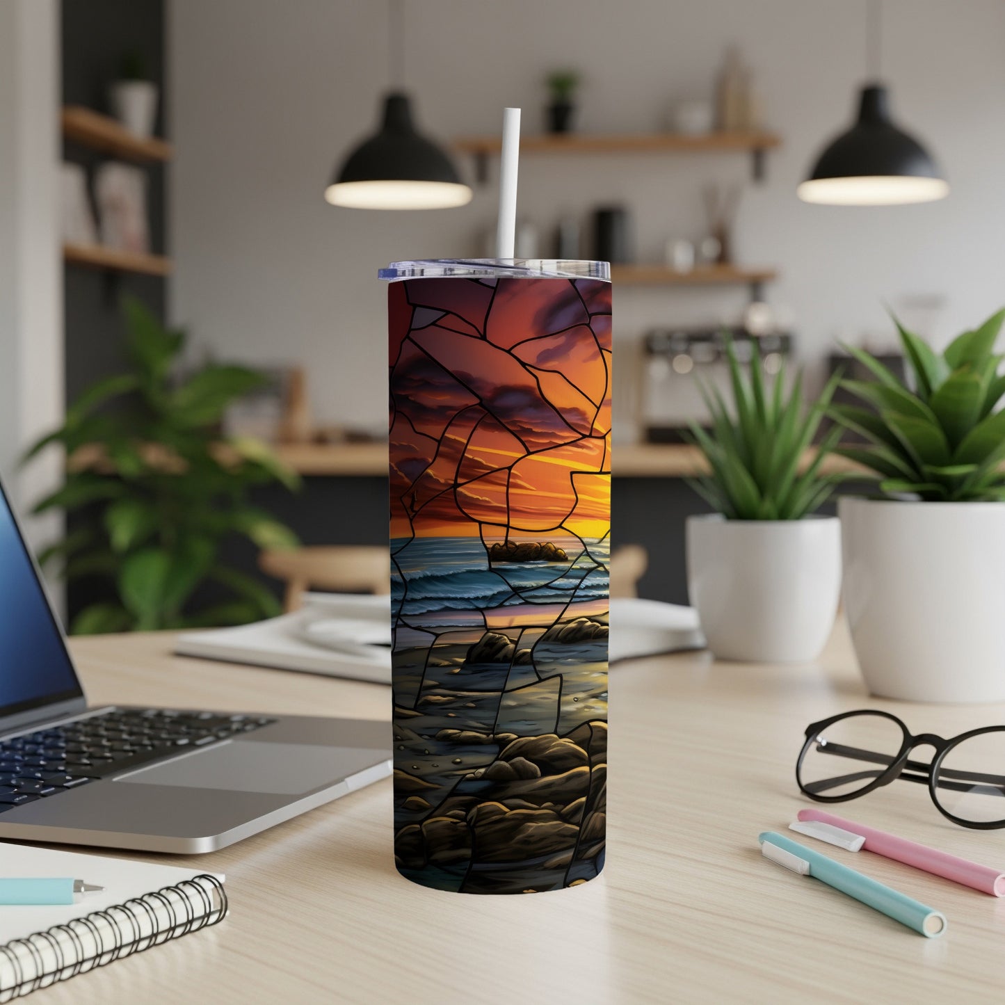 Stained glass sunset scene on a tumbler, resting on a desk.