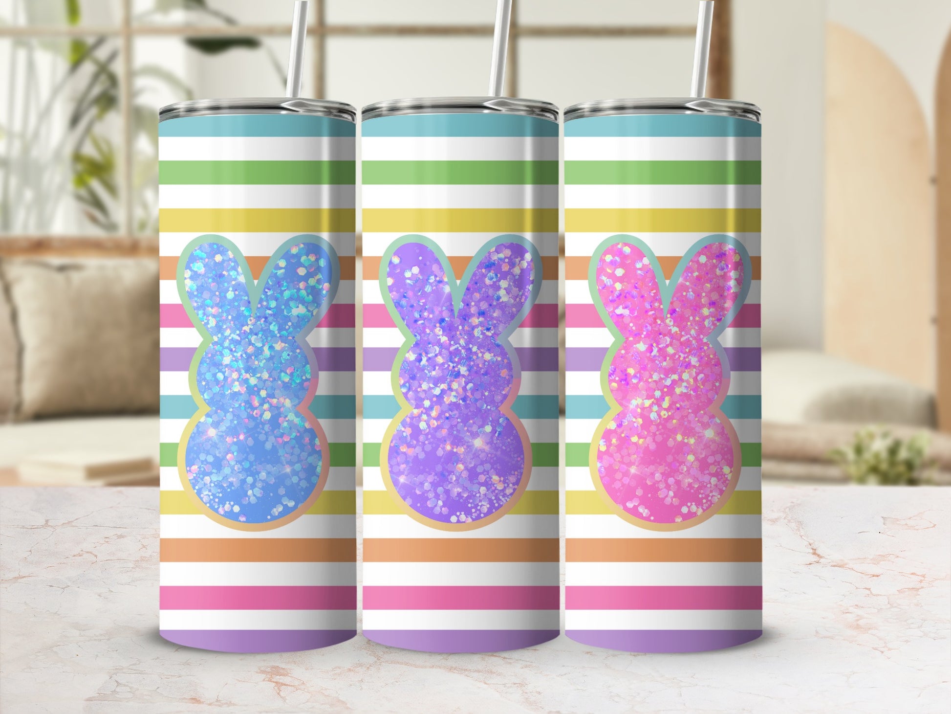 Three glitter bunny tumblers with colorful stripes, on a marbled surface.
