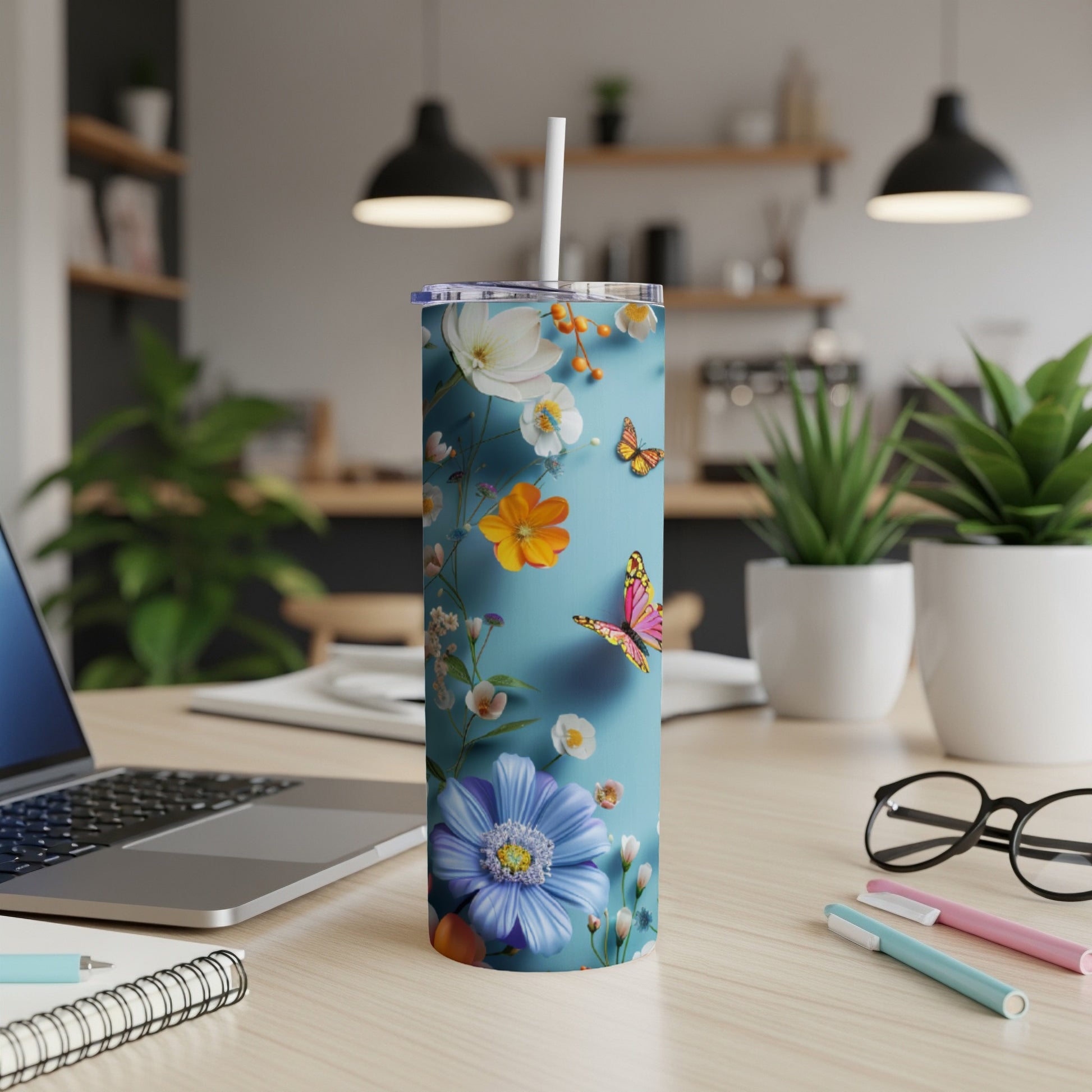 Floral and butterfly pattern on a blue skinny tumbler with a white straw.