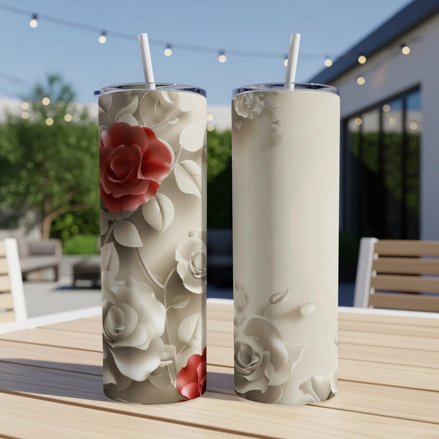 Two tumblers with rose floral design sit on a wooden table outdoors.