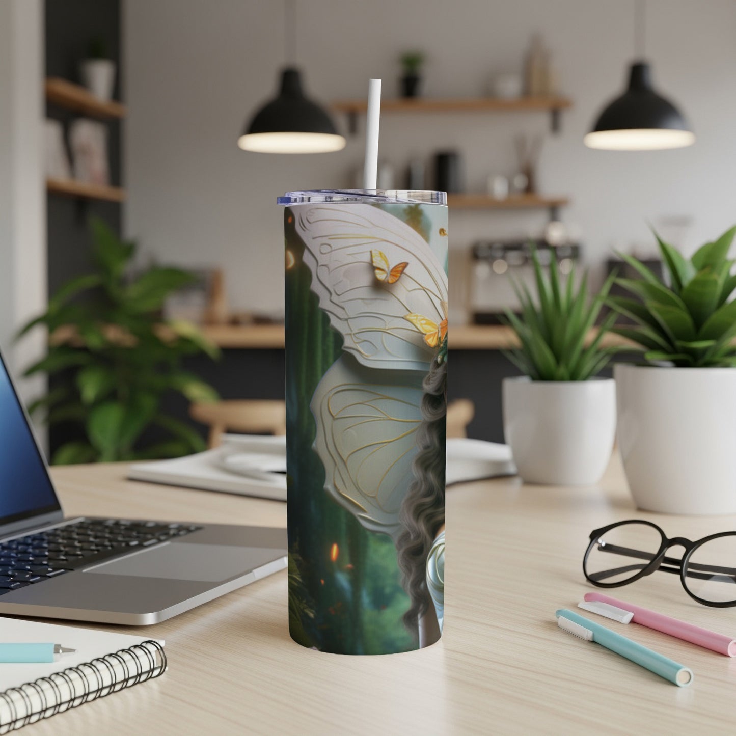 A white tumbler with butterfly wings and fairy imagery on a desk.
