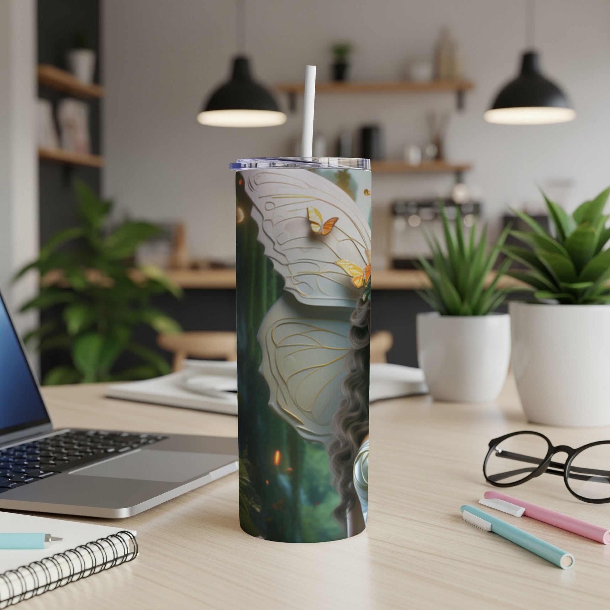 A white tumbler with butterfly wings and fairy imagery on a desk.