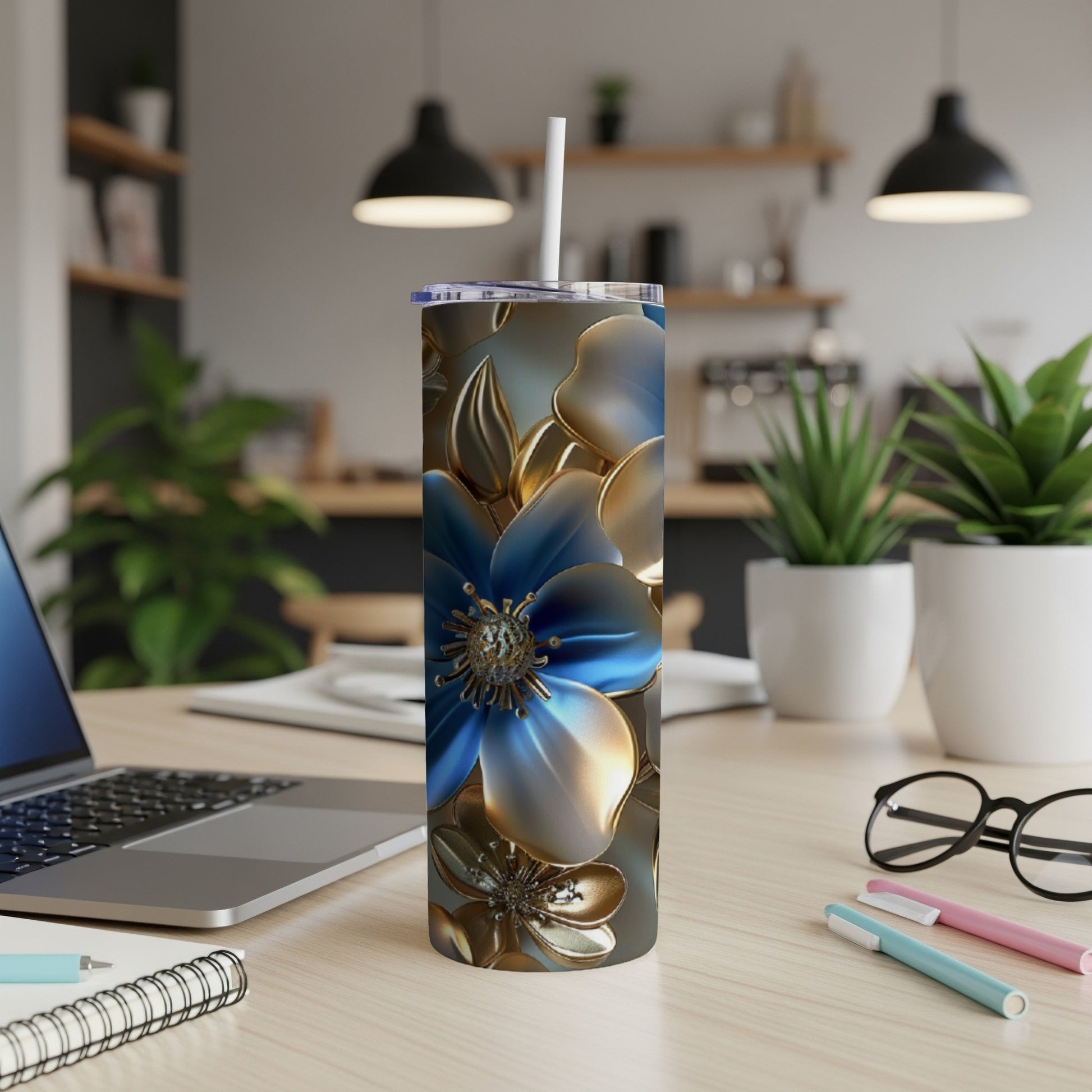 Blue and gold floral patterned tumbler on a desk with laptop and pens.