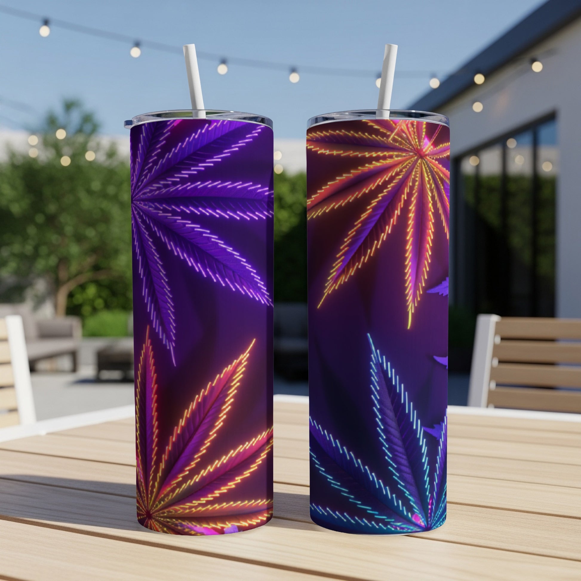 Two tumblers with neon cannabis leaf designs on a patio table.