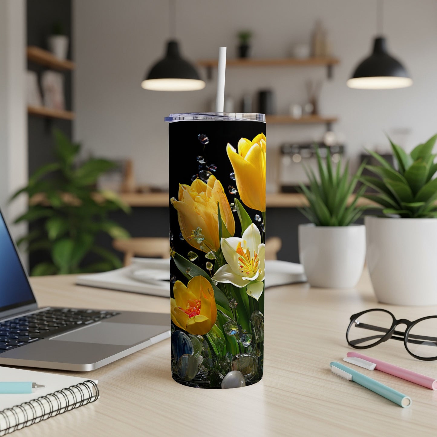 Tumbler with yellow tulips and water droplets on a desk.