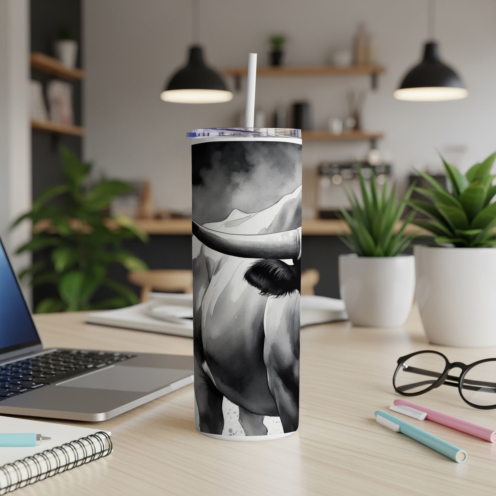 Black and white tumbler with bull graphic, set on a desk.