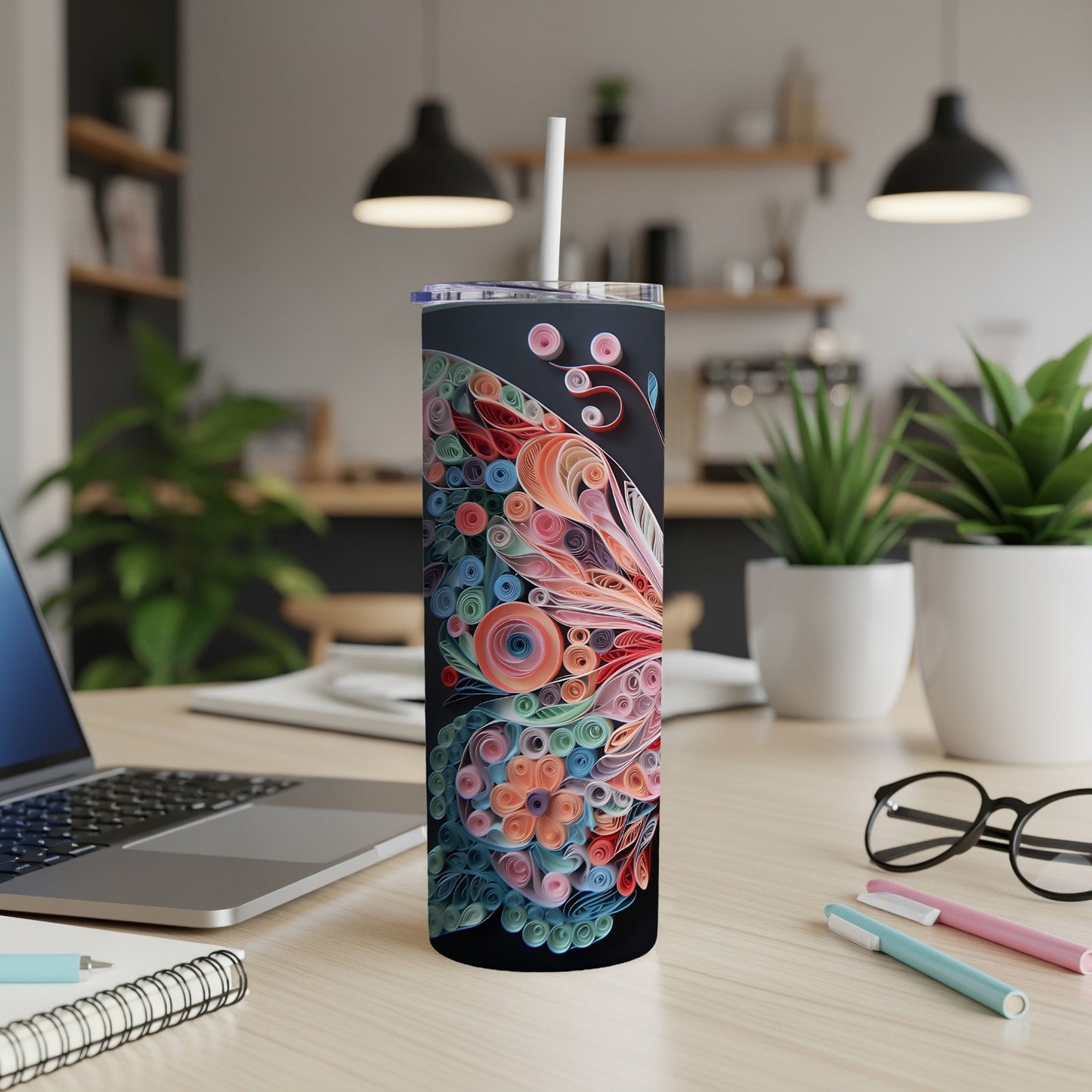 Black tumbler with colorful floral quilling pattern and white straw on a desk.