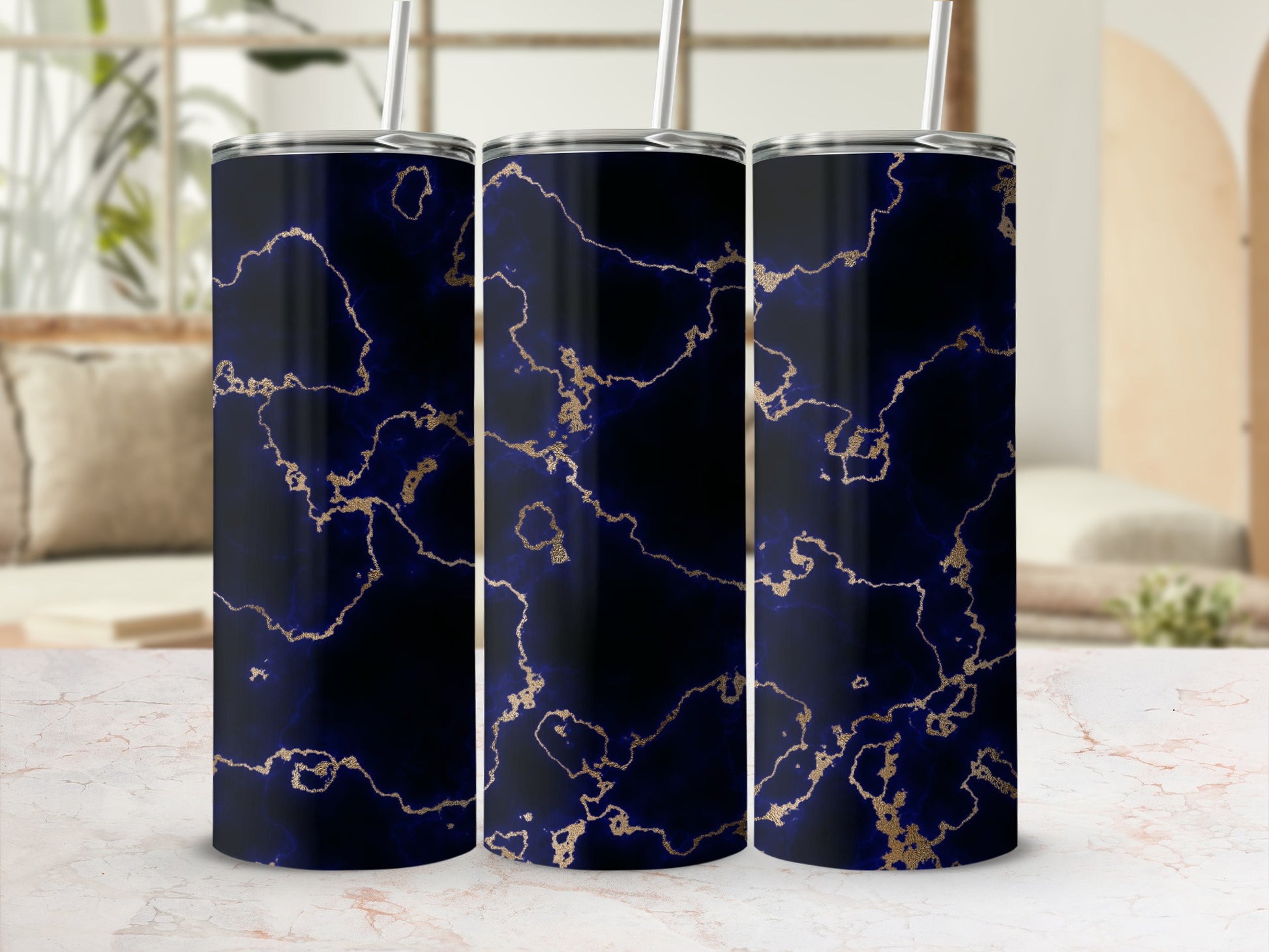 Three dark blue tumblers with gold marble pattern and straws.