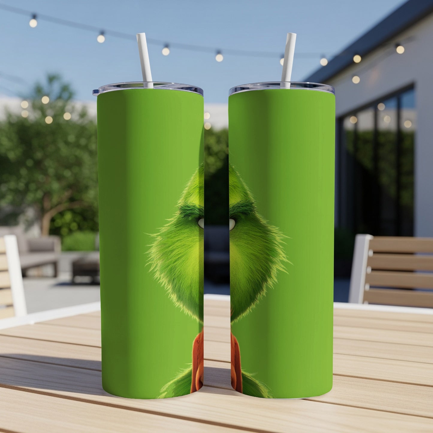 Green tumbler with close-up Grinch face, white straw, outdoor setting.