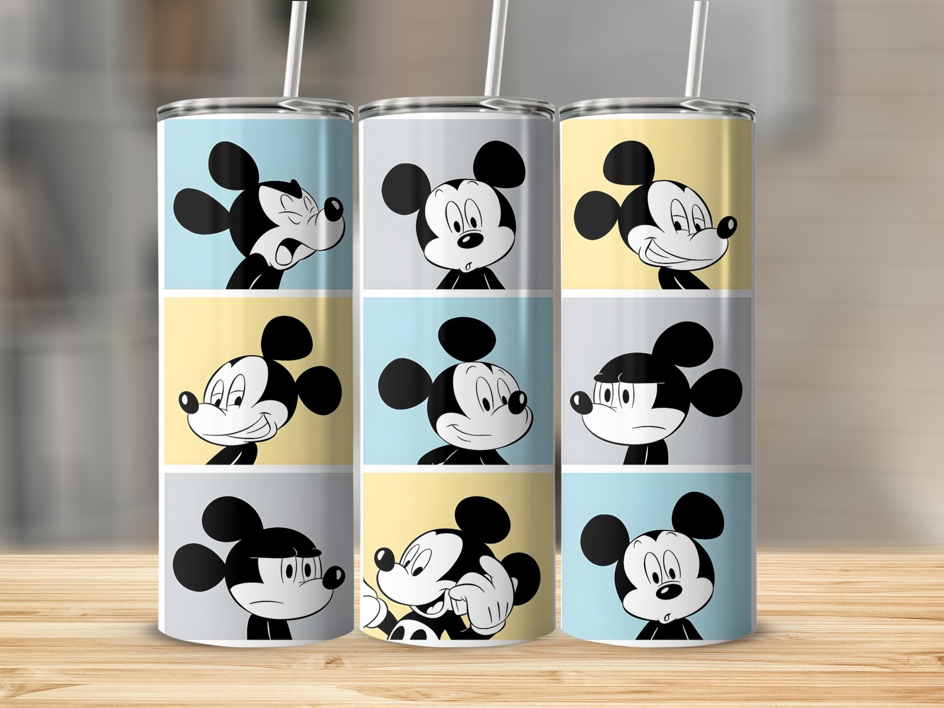 Three tumblers with Mickey Mouse expressions on a wooden surface.