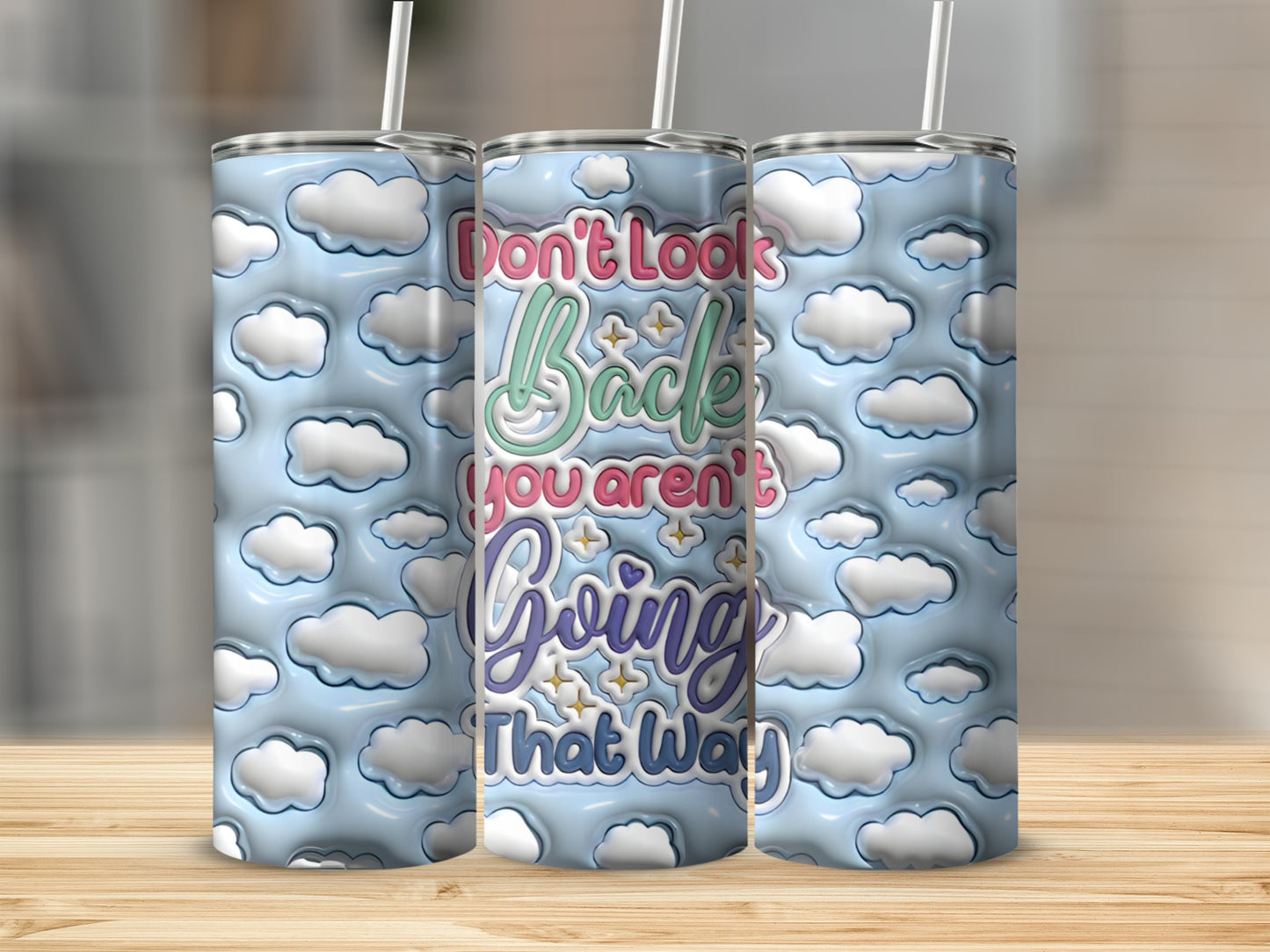 Blue tumbler with white clouds and colorful text "Don't look back, you aren't going that way".