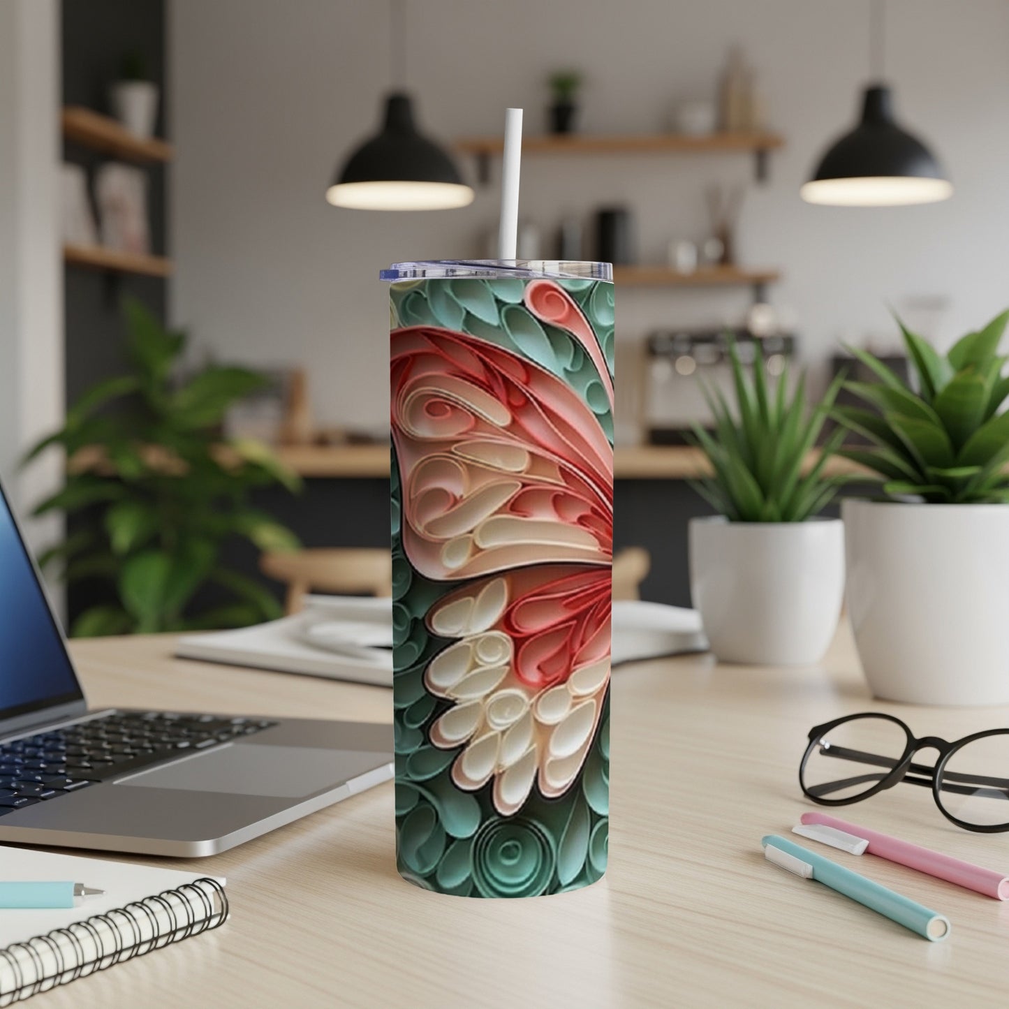 Pink and teal quilled butterfly tumbler with straw on a desk.
