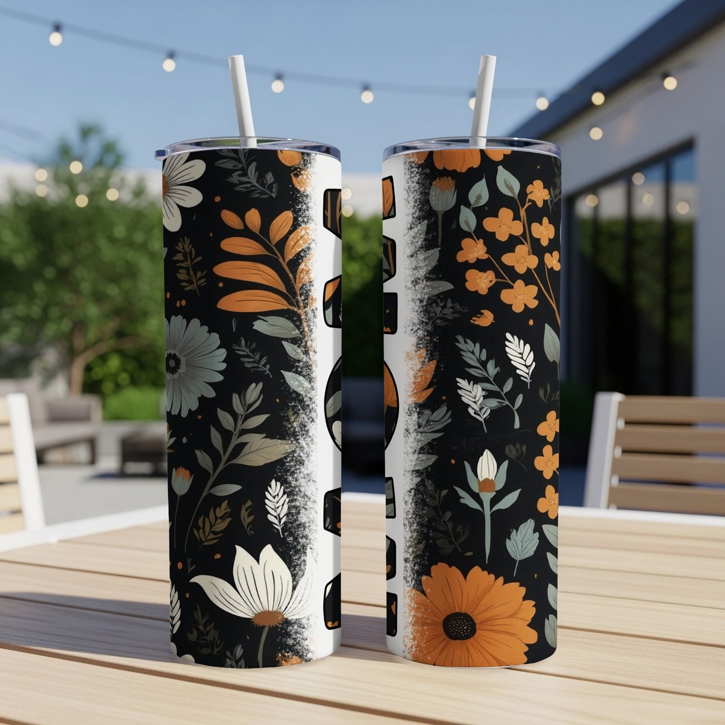 Two tumblers with a floral pattern and straw on a table.