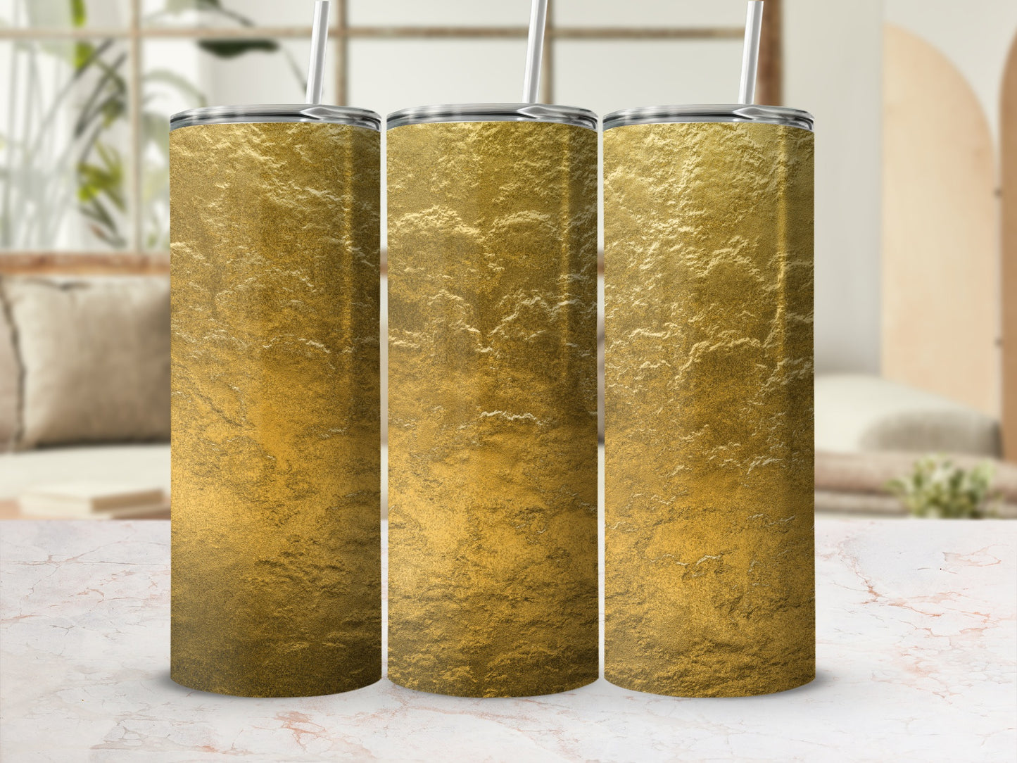 Three tall, gold textured tumblers with silver lids and straws stand in a row.
