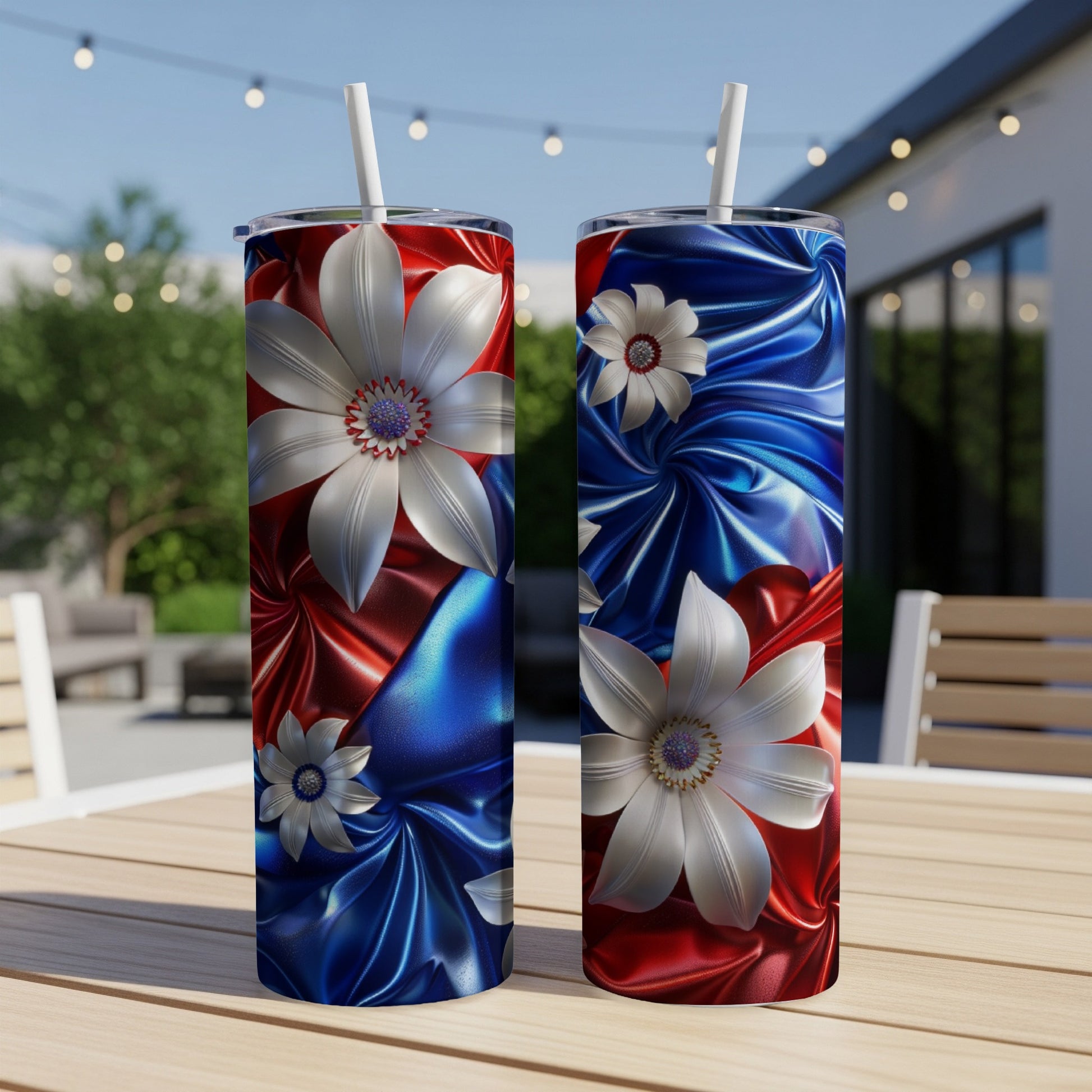 Two tall tumblers with red, white, and blue floral design on outdoor table.
