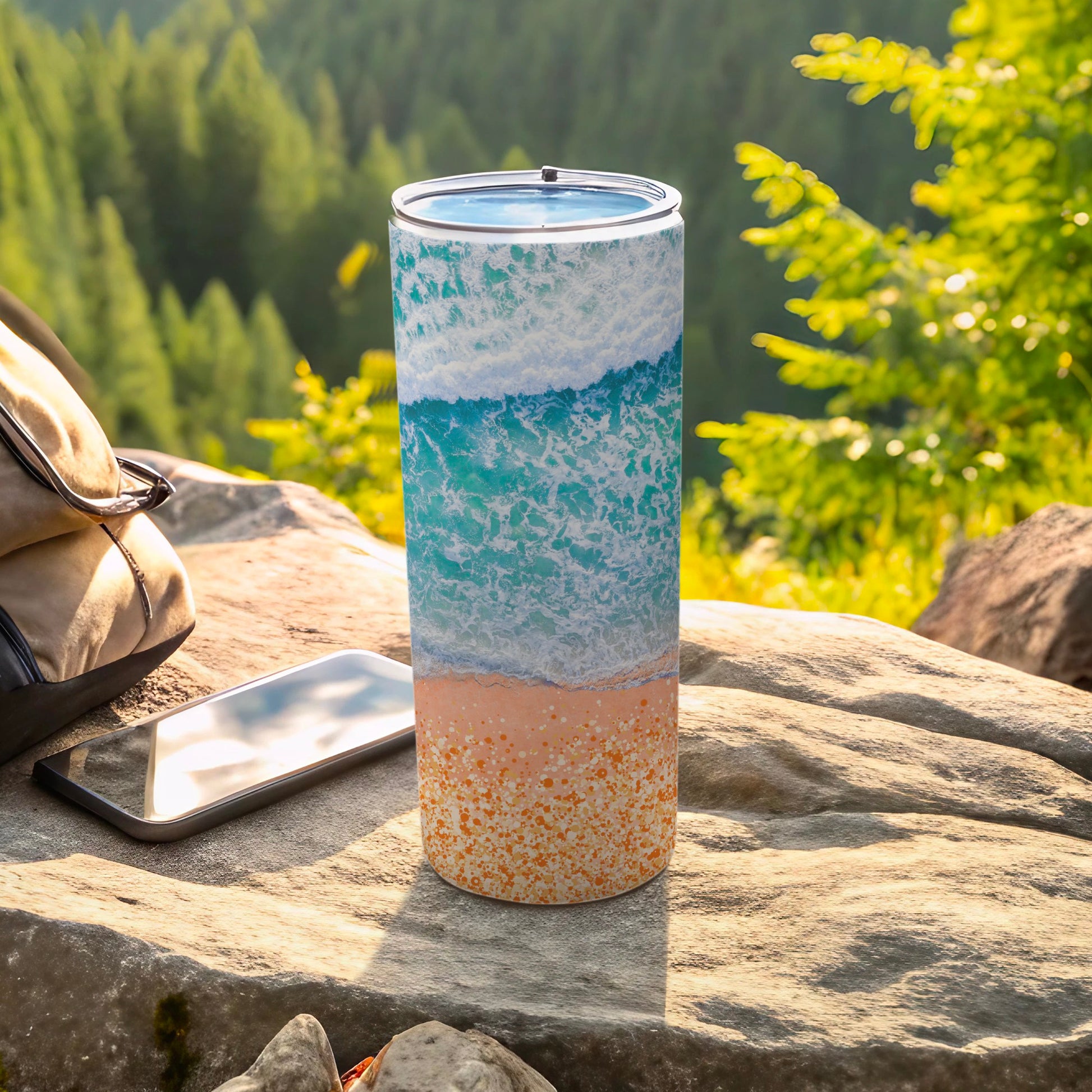Beach wave and sand pattern on a cylindrical tumbler with a phone and bag.