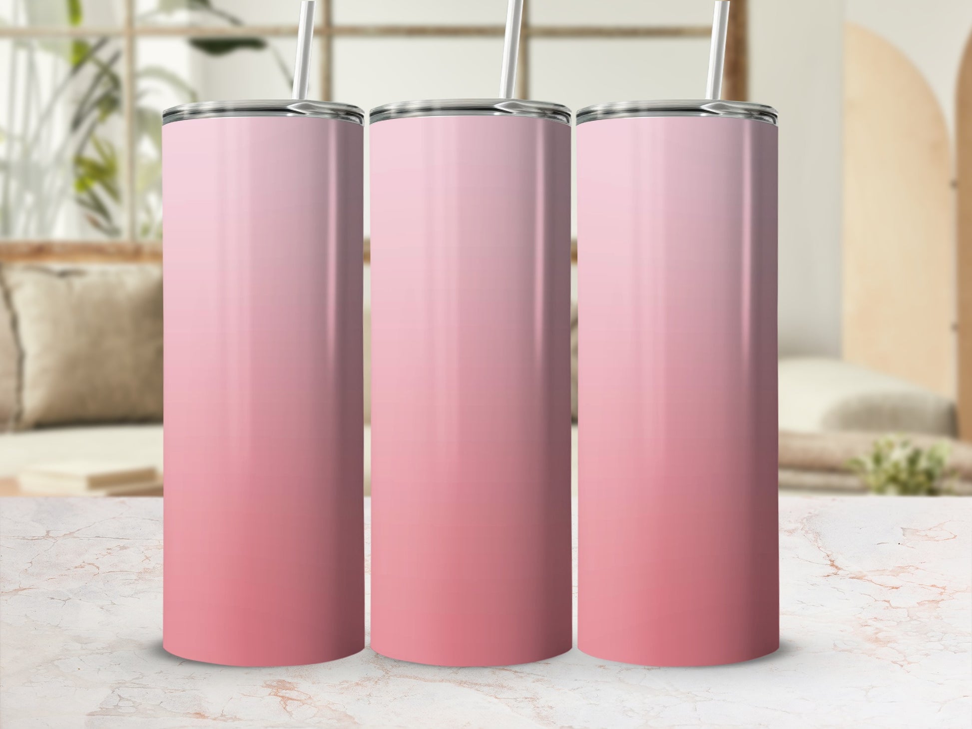 Three pink gradient tumblers with straws on a marble countertop.