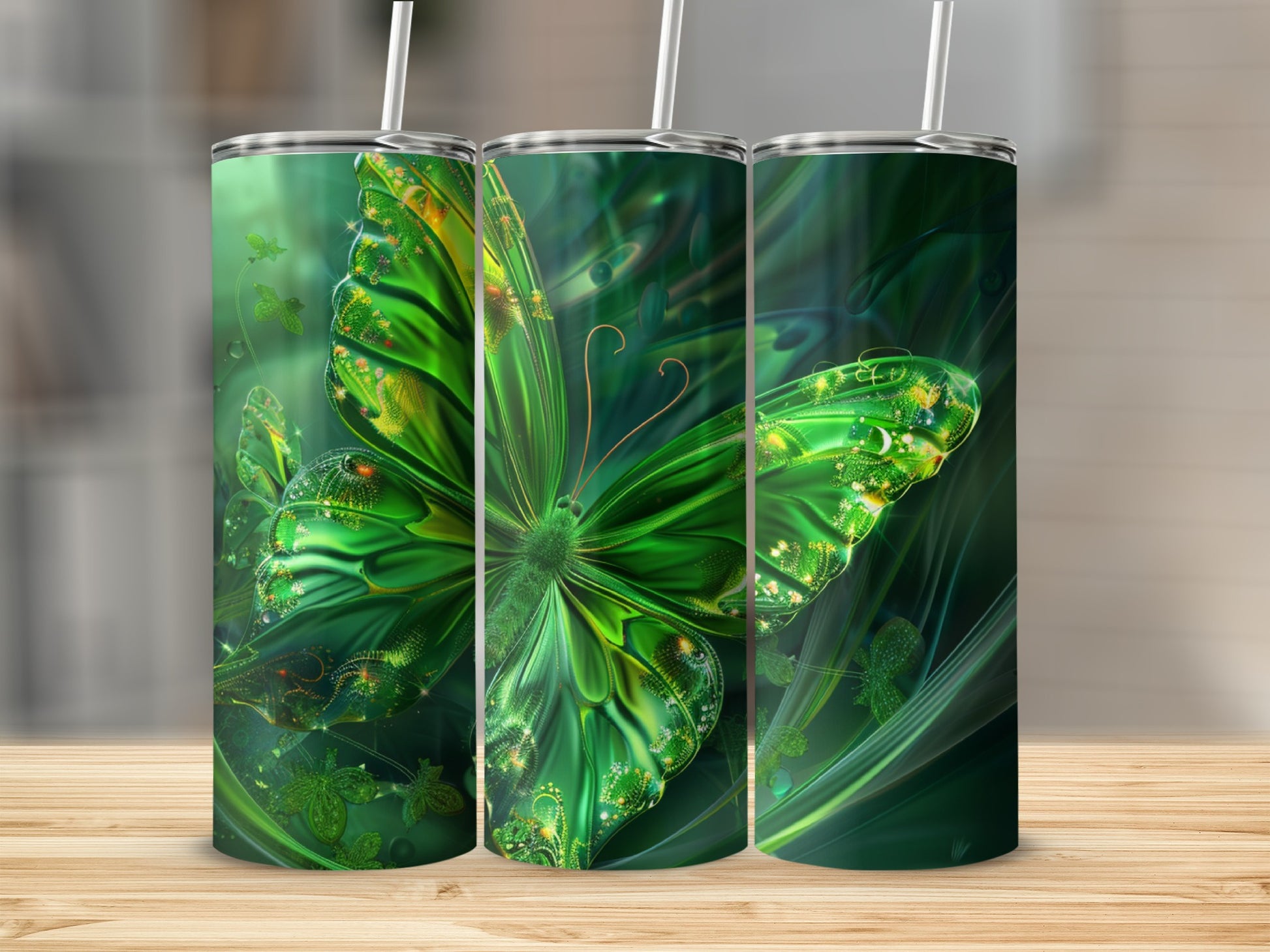 Three tumblers with a green, glowing butterfly design on a wooden surface.