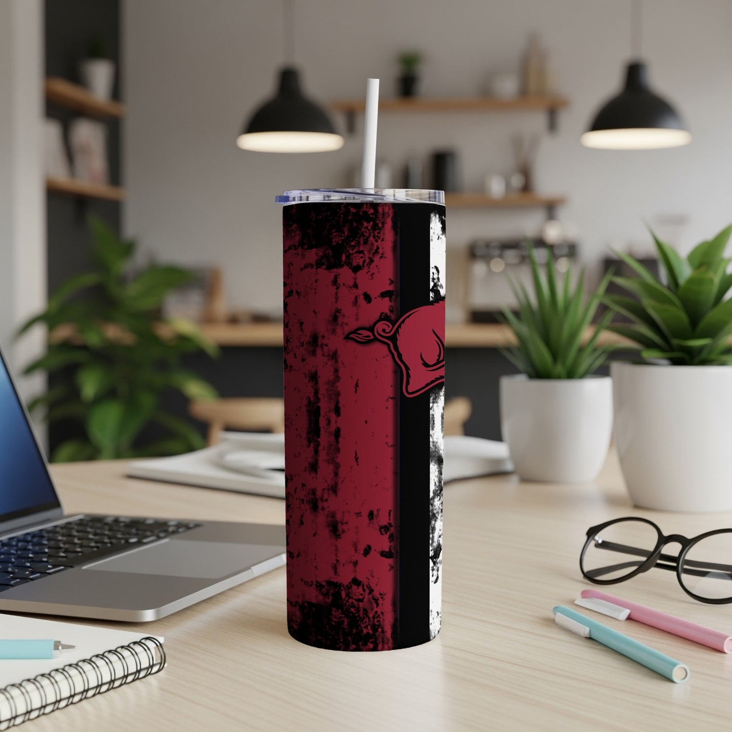 Red and black grunge tumbler with a pig logo on a desk.