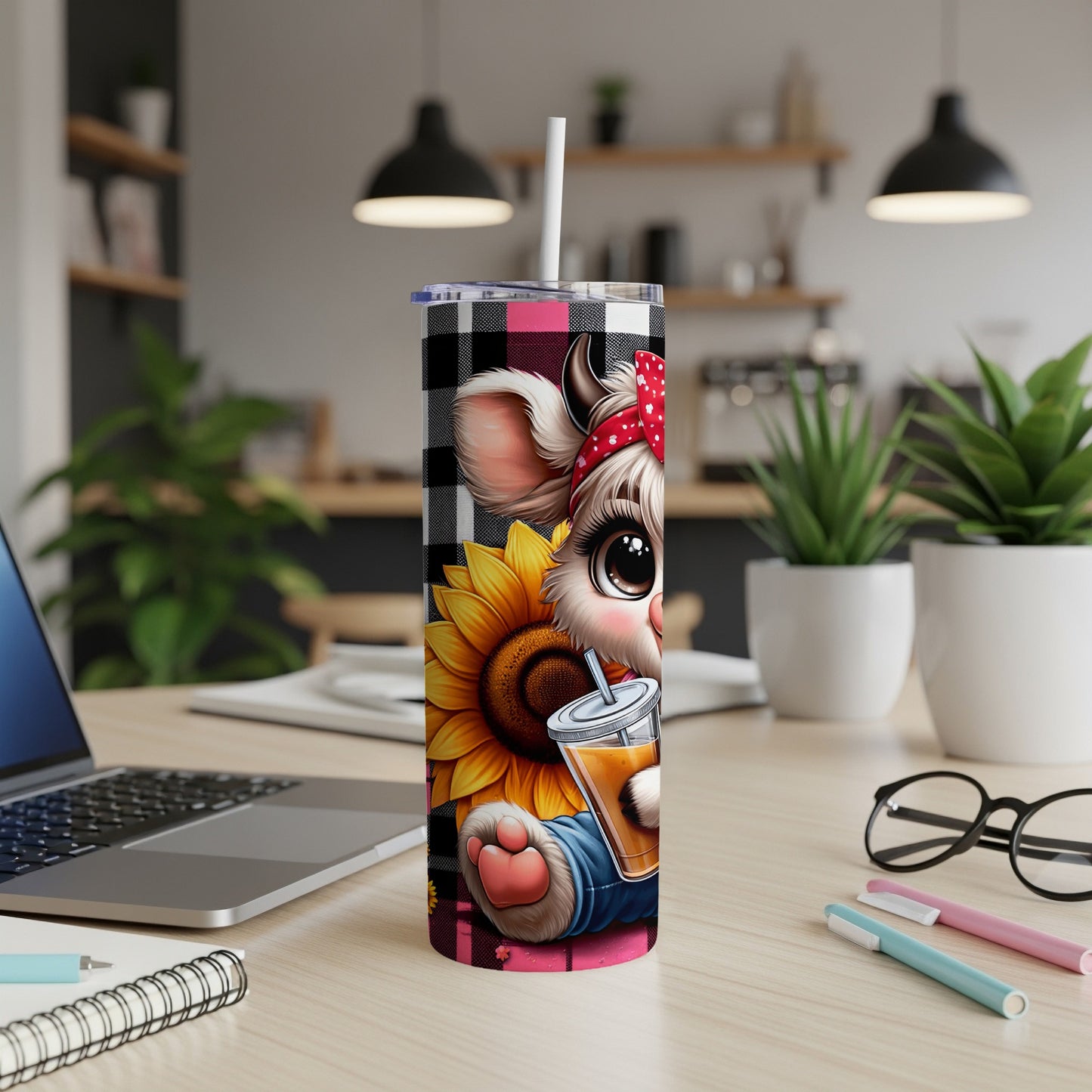 Cartoon cow in bandana holding orange juice on desk with laptop and pens.