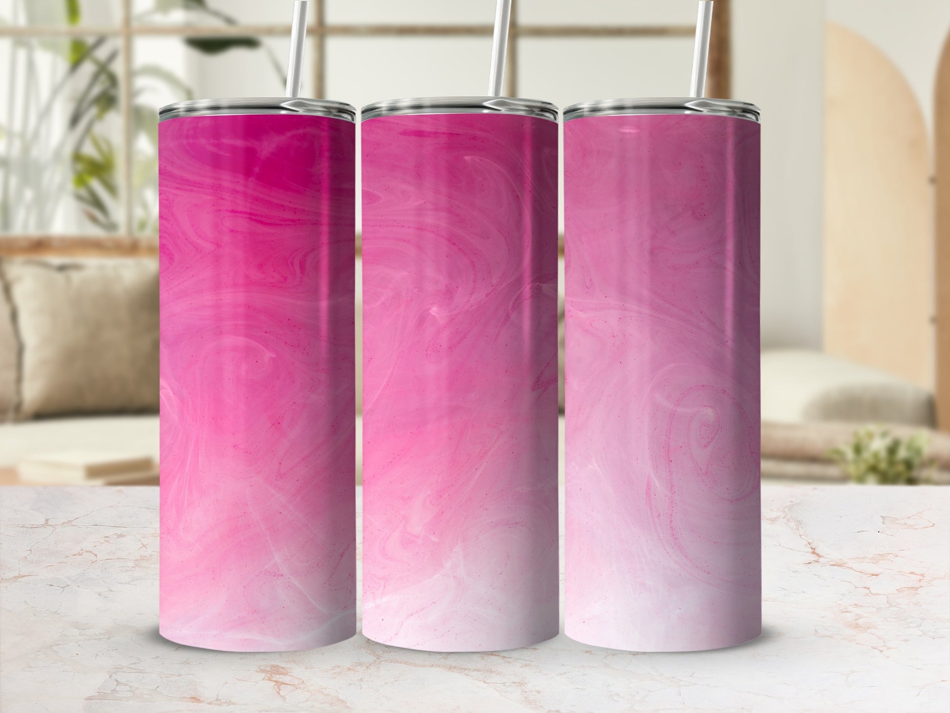 Three pink gradient tumblers with straws on a marble surface.