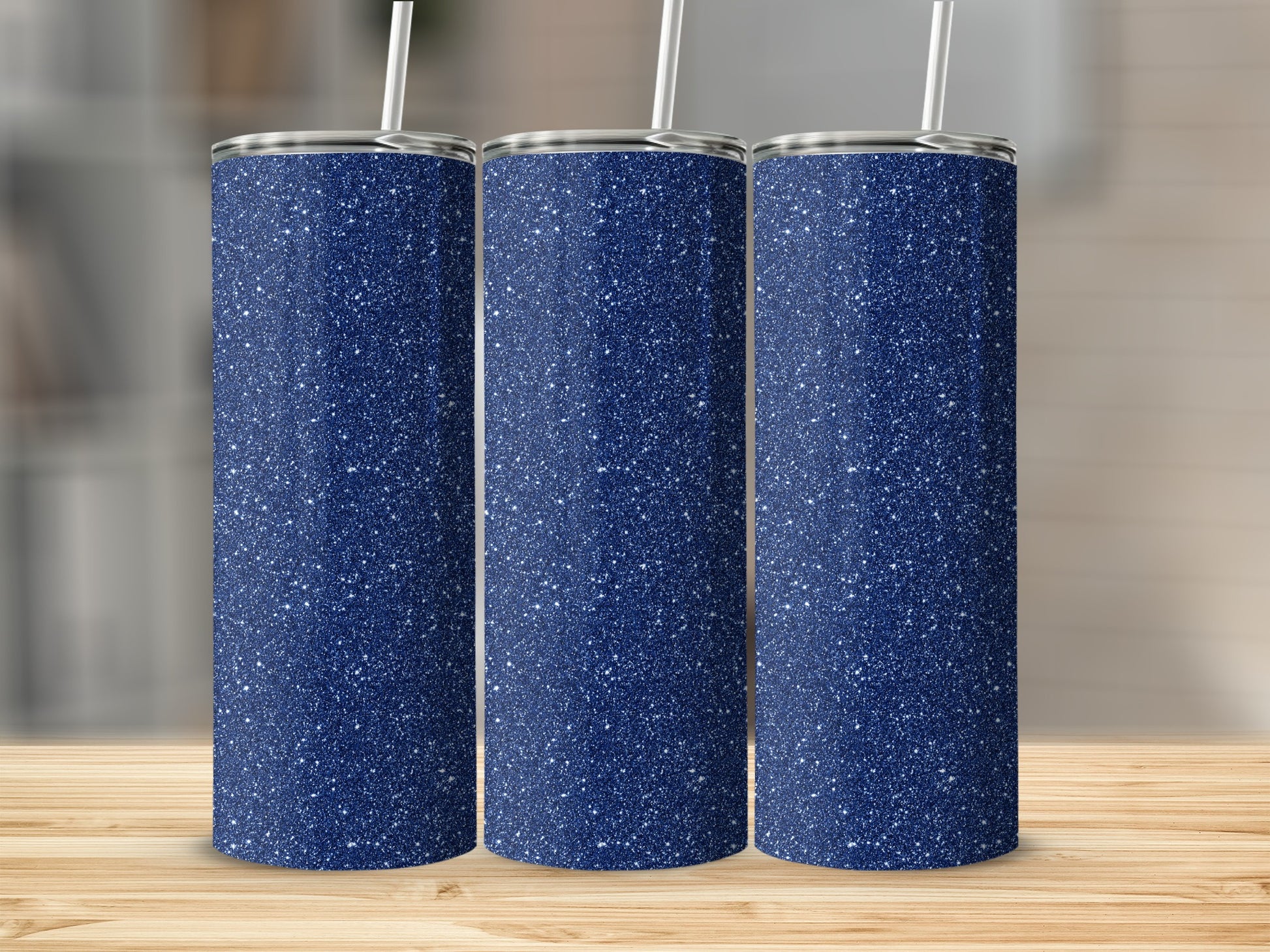 Three navy blue glitter tumblers with white straws on a wooden surface.