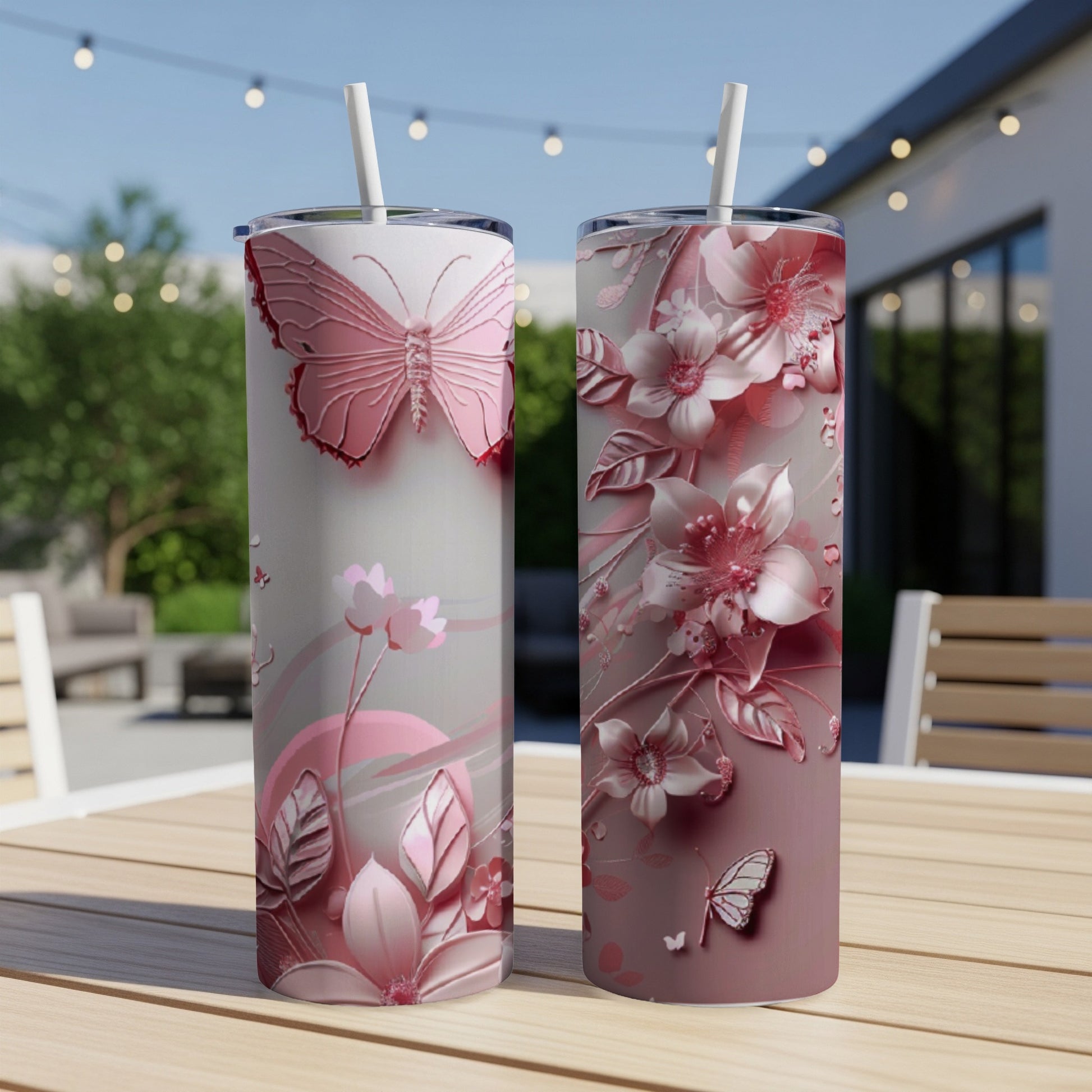 Two pink tumblers with butterfly and floral embossed designs on a table.