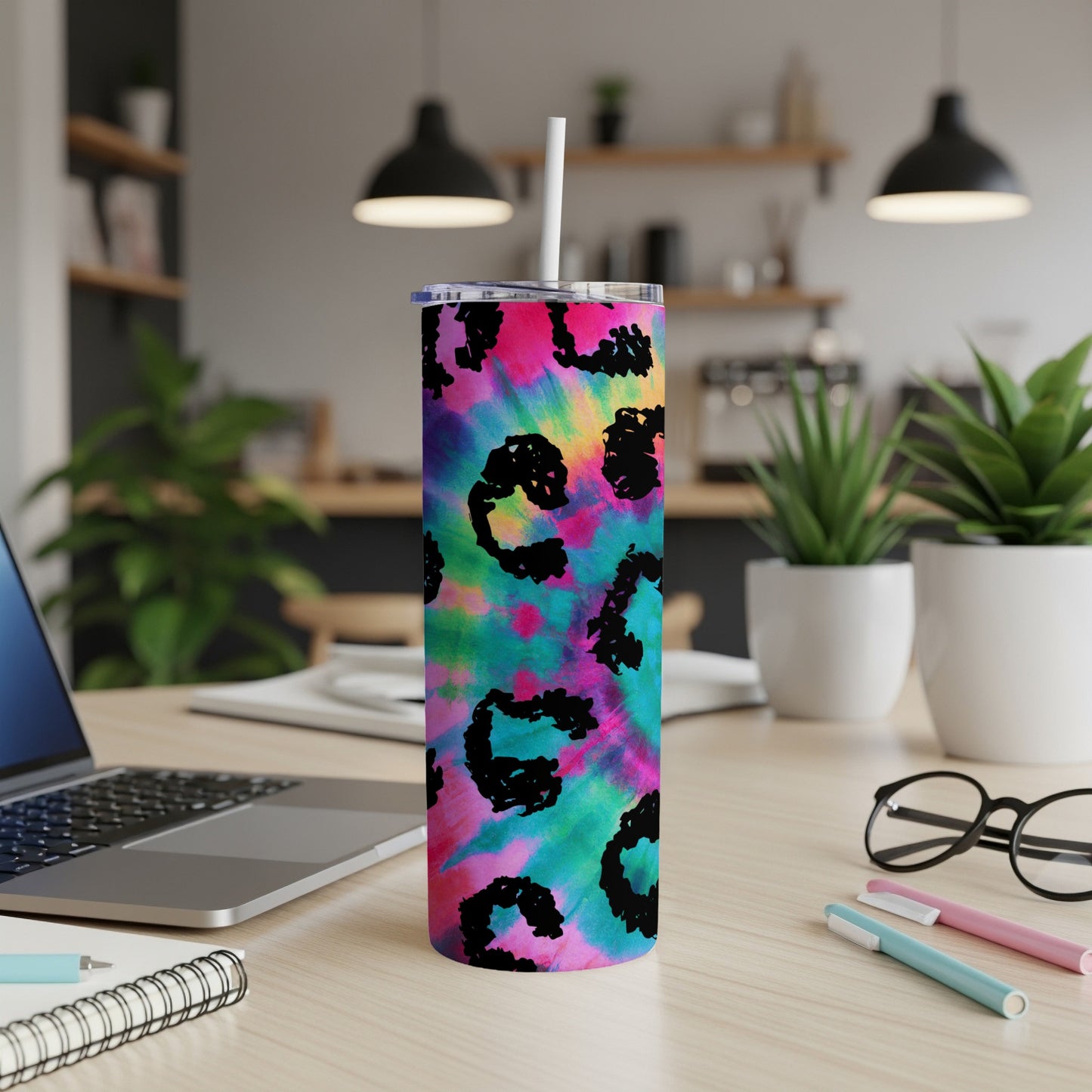 Tie-dye tumbler with black leopard print pattern on desk.