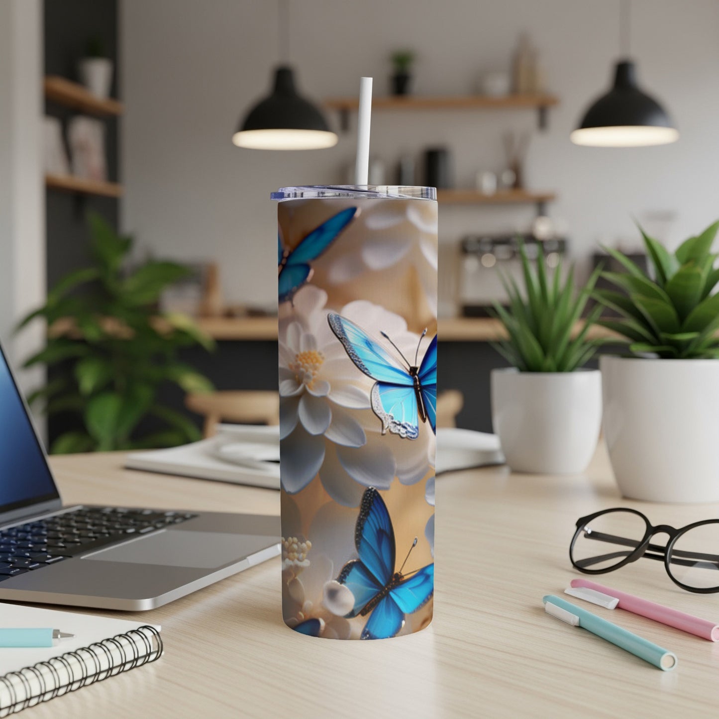 Tumbler with blue butterflies and white flowers on a desk.