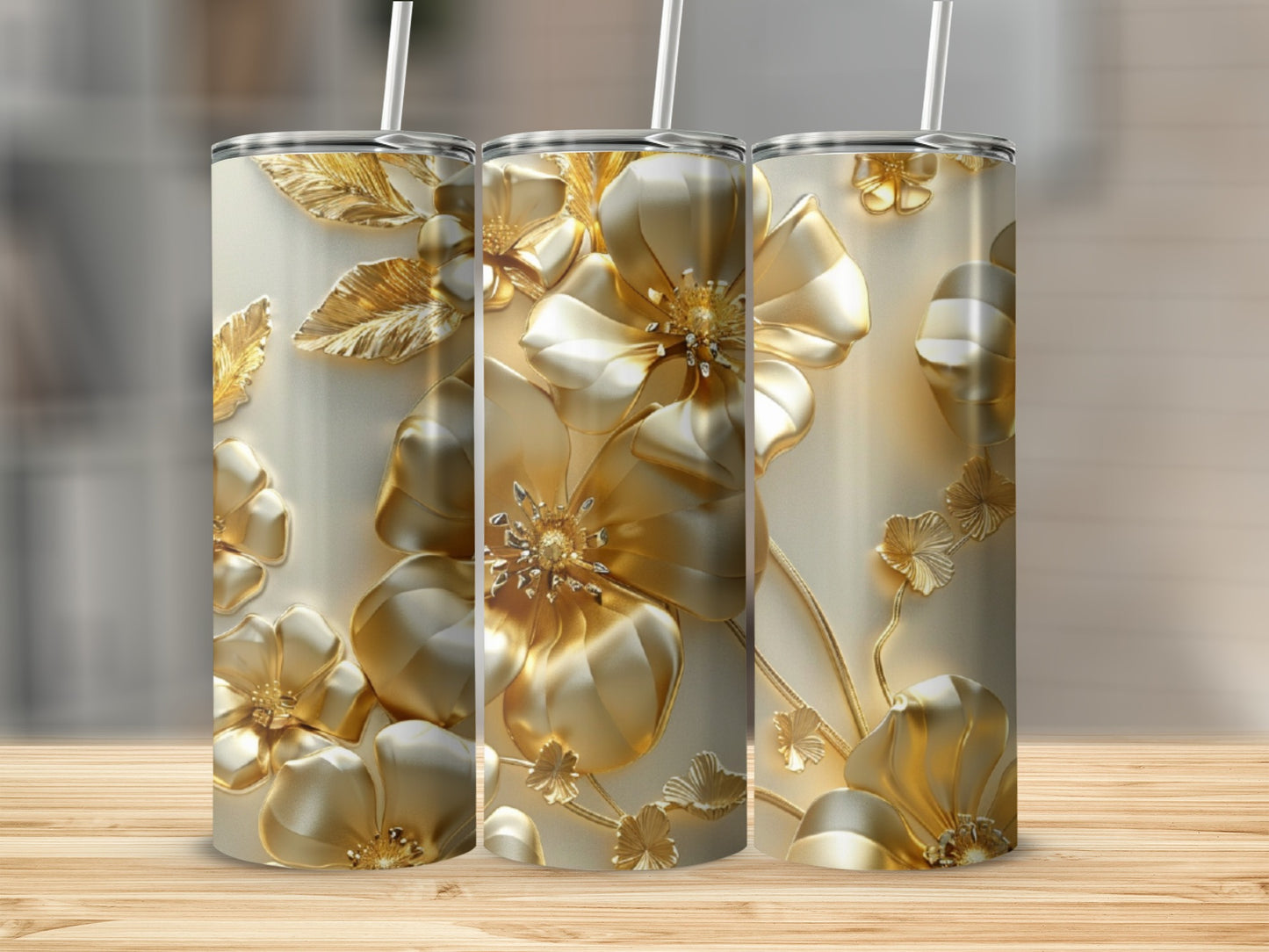 Three gold tumblers with embossed floral designs on a wooden surface.