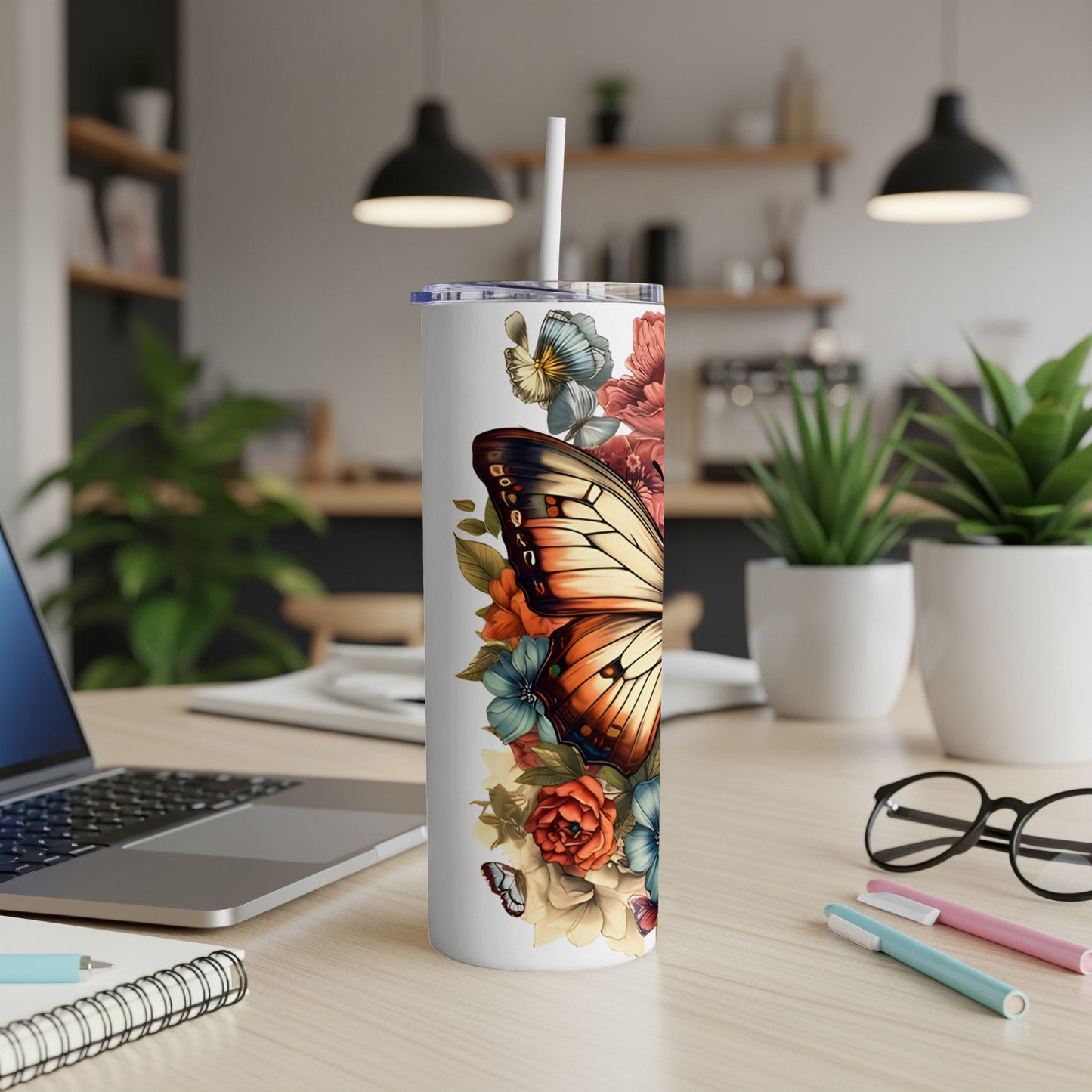 Tumbler with butterfly and floral design on a desk.