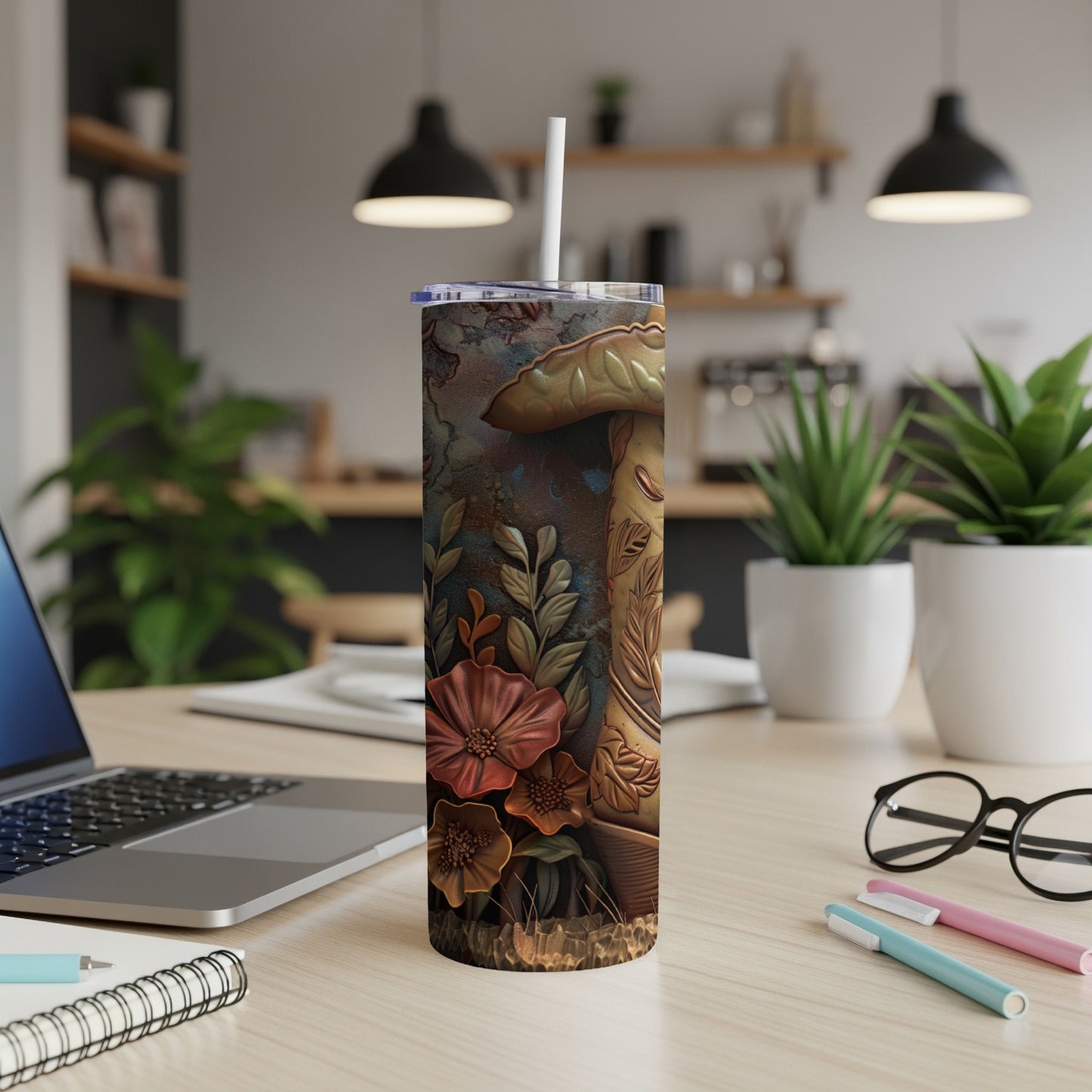 Tumbler with mushroom and floral design on a desk.