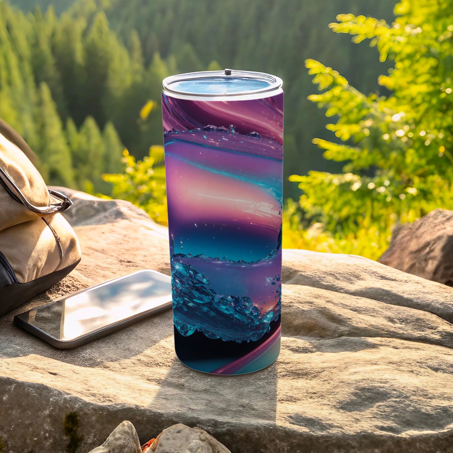 Tumbler with abstract purple and blue swirl design on rocky outdoor surface.