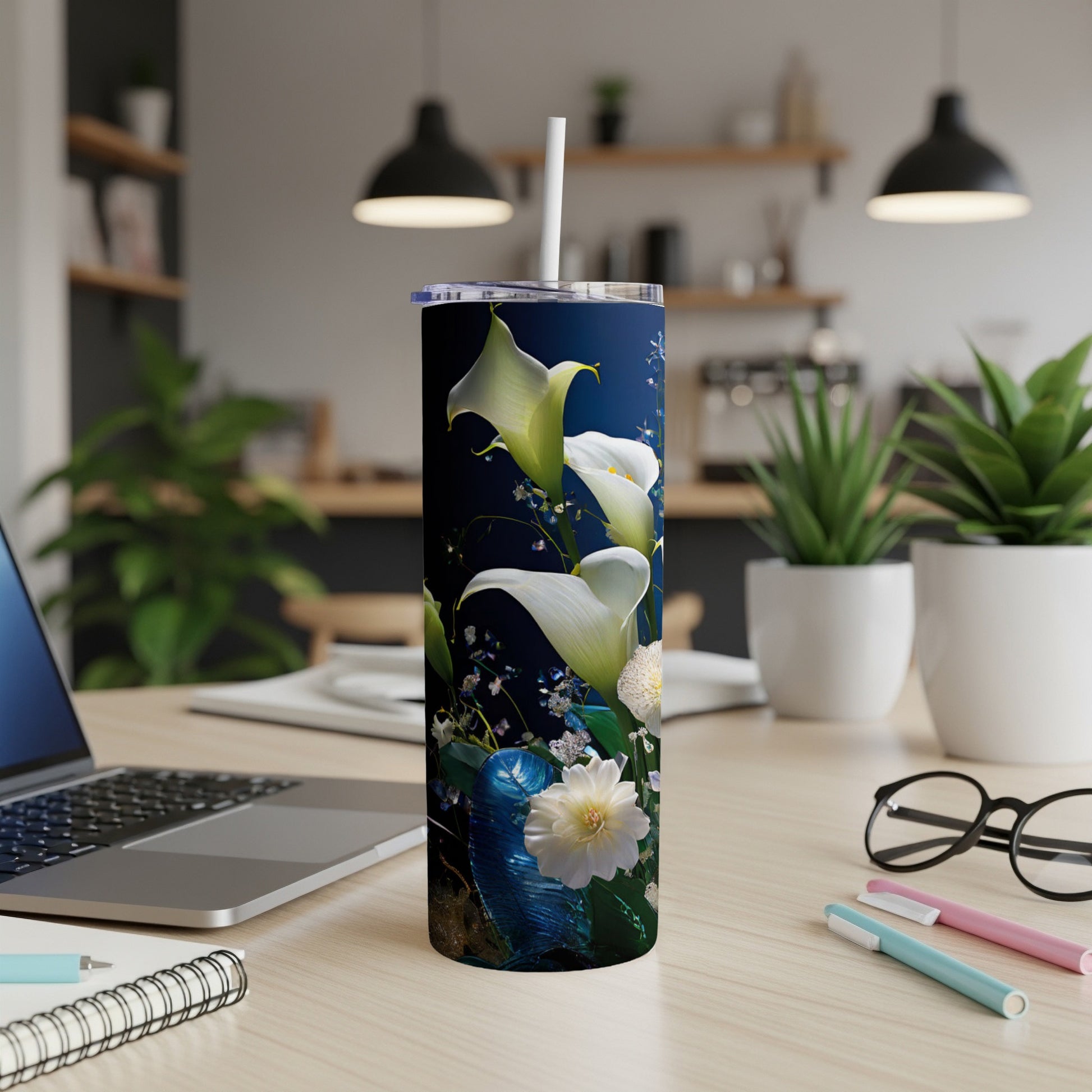 White calla lilies and green leaves on a dark blue tumbler with a straw.