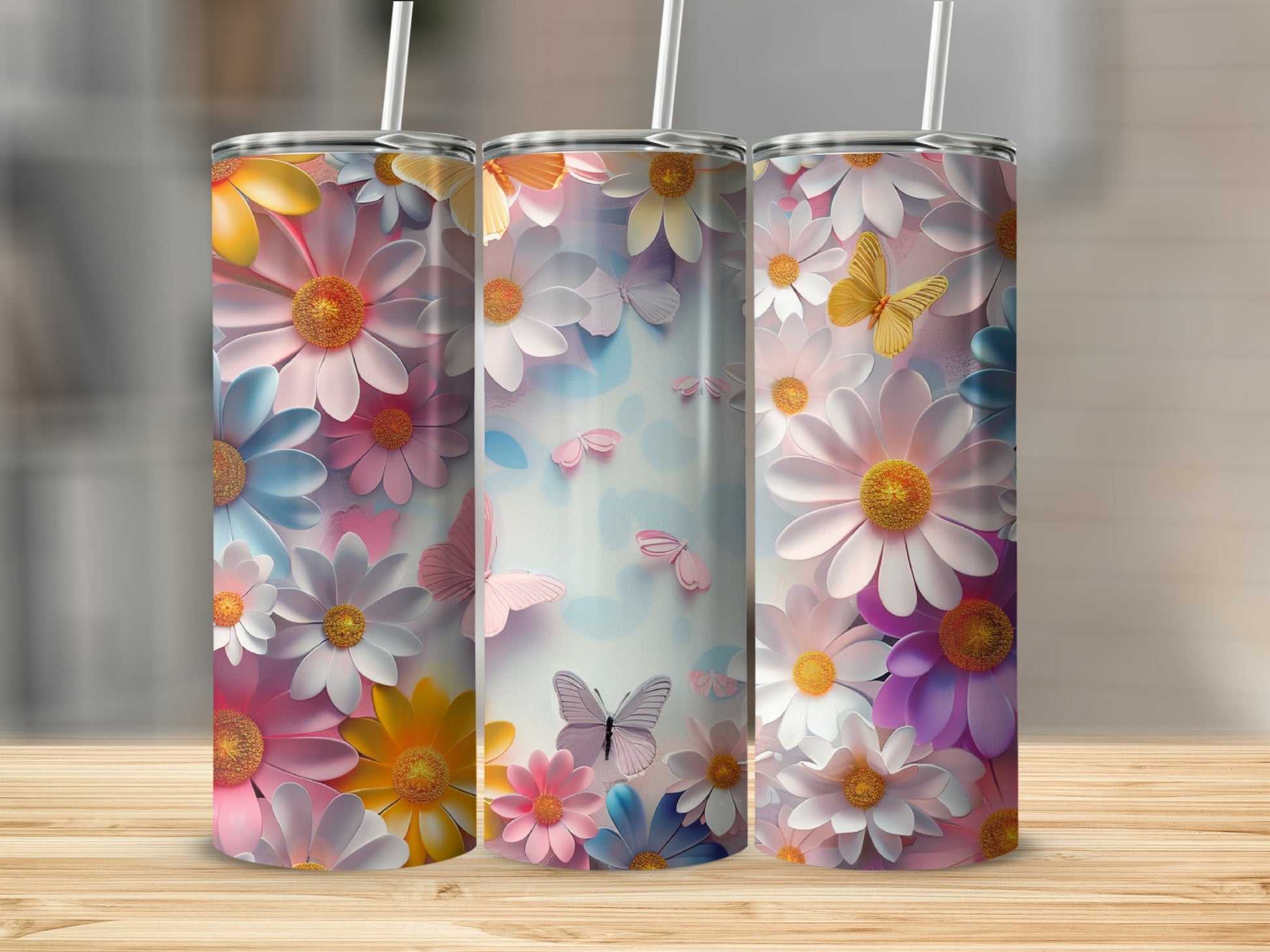 Three tumblers with pastel floral and butterfly designs on a wooden surface.