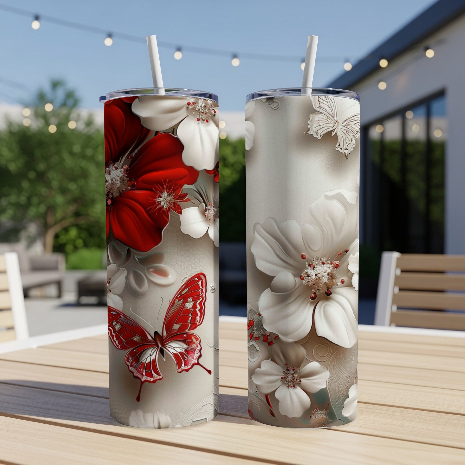 Two tumblers with red and white flowers and butterfly design on a table.