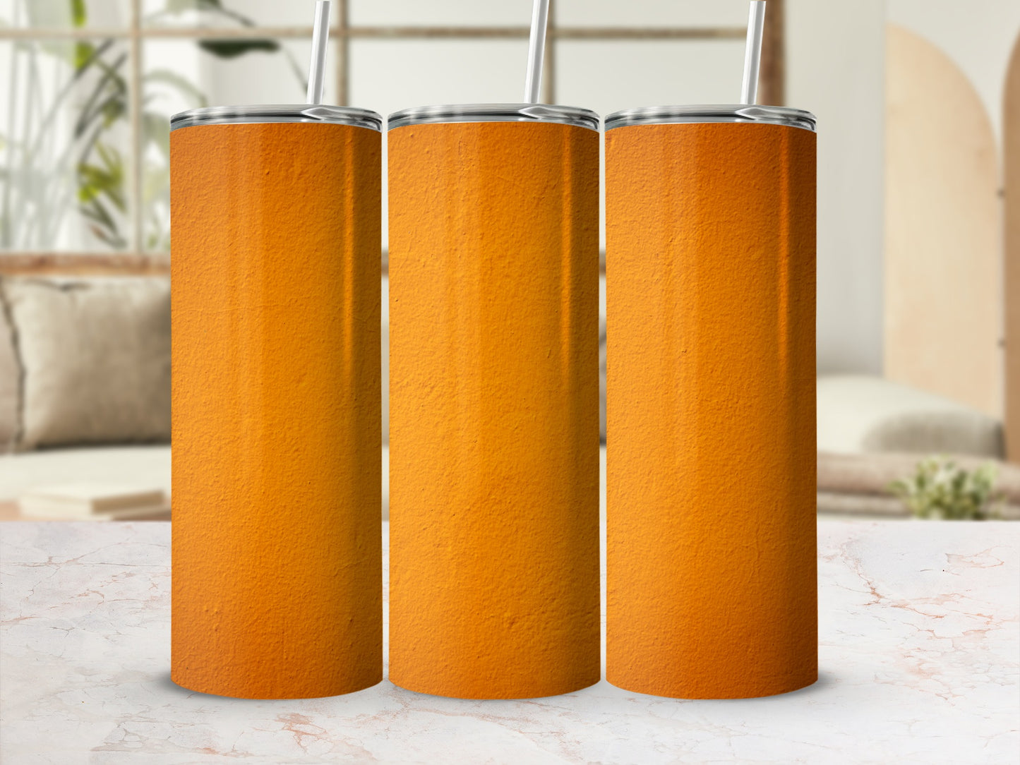 Three orange textured tumblers with straws stand on a marble surface.
