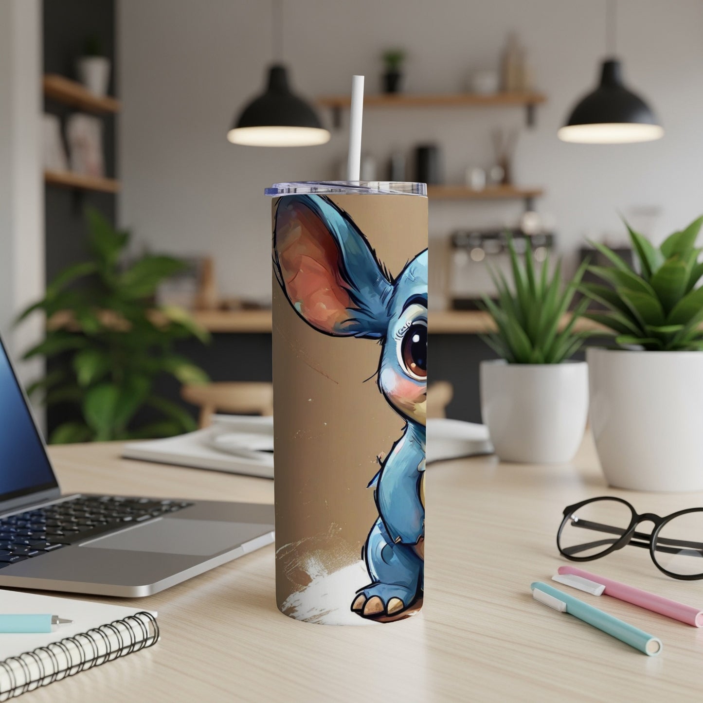 Cartoon Stitch character on a tall, skinny tumbler with straw on a desk.