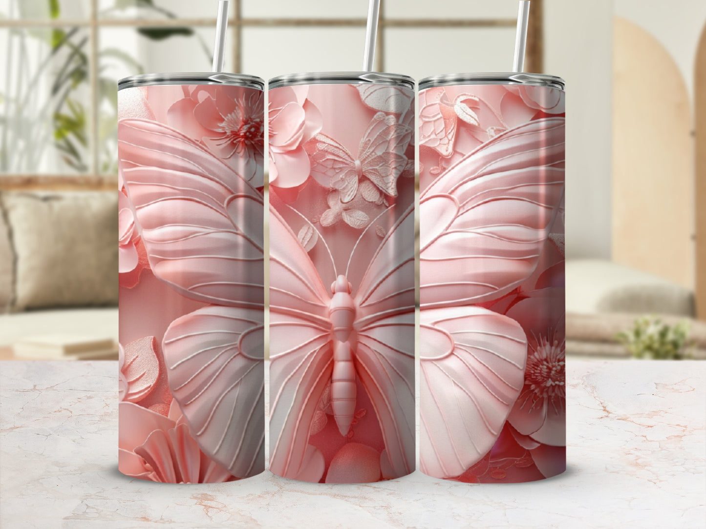 Three pink butterfly and floral pattern tumblers with straws, displayed on a marble surface.