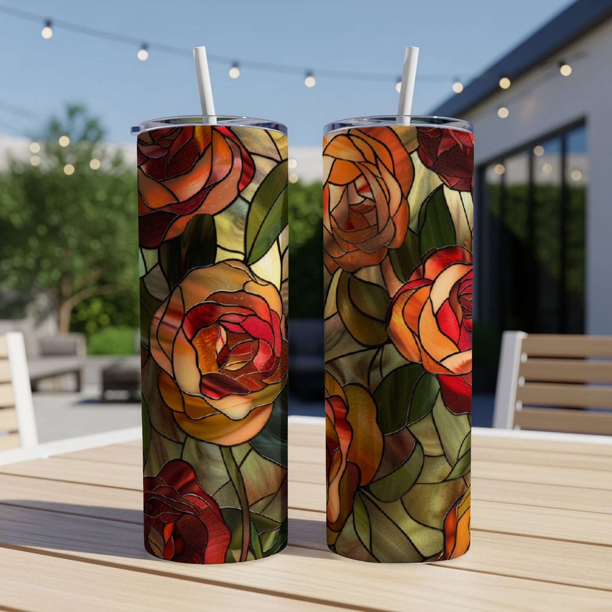 Two tumblers with a stained-glass rose design on an outdoor table.